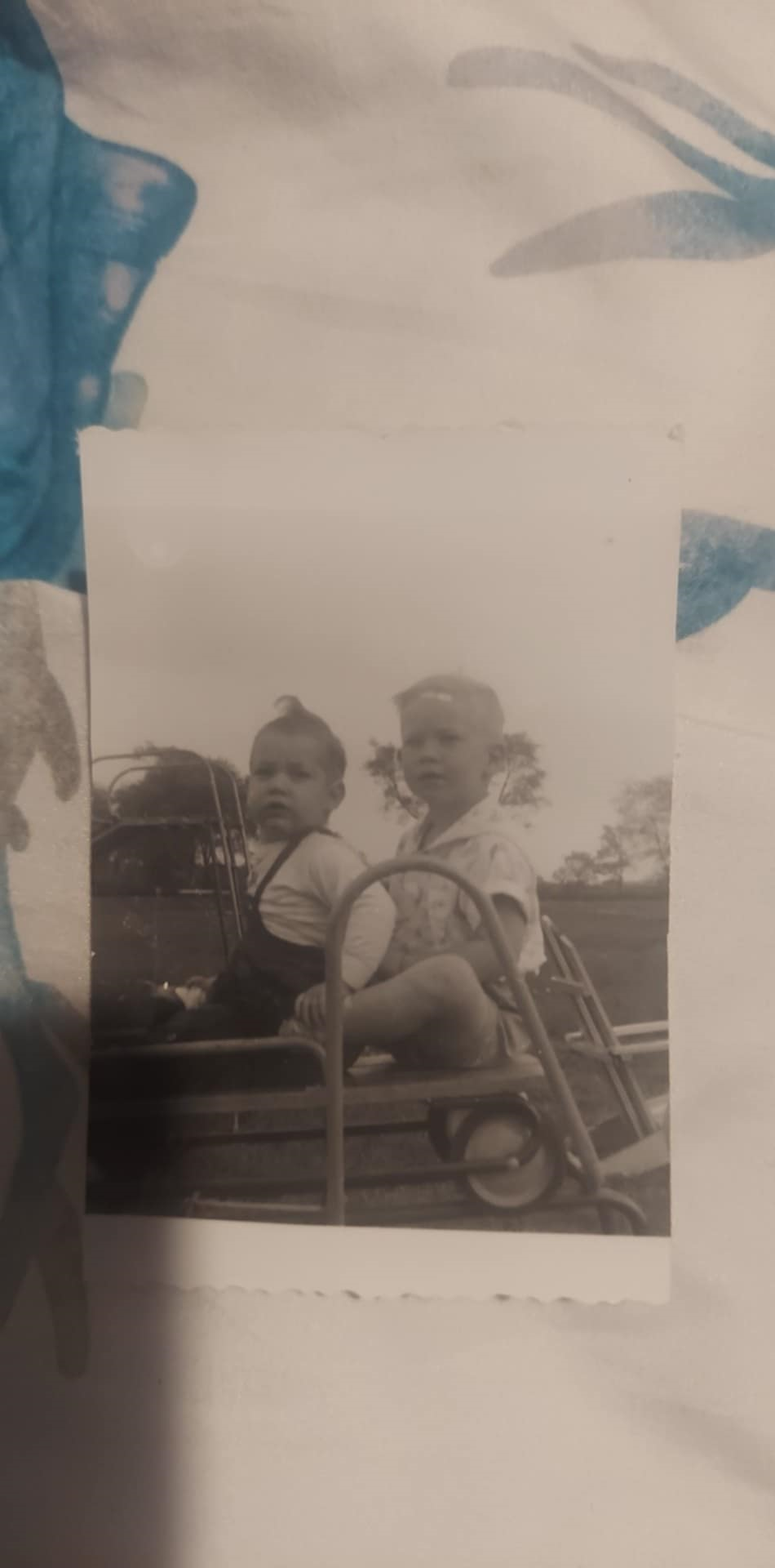 Two young children are sitting together on playground equipment, enjoying their time outdoors.