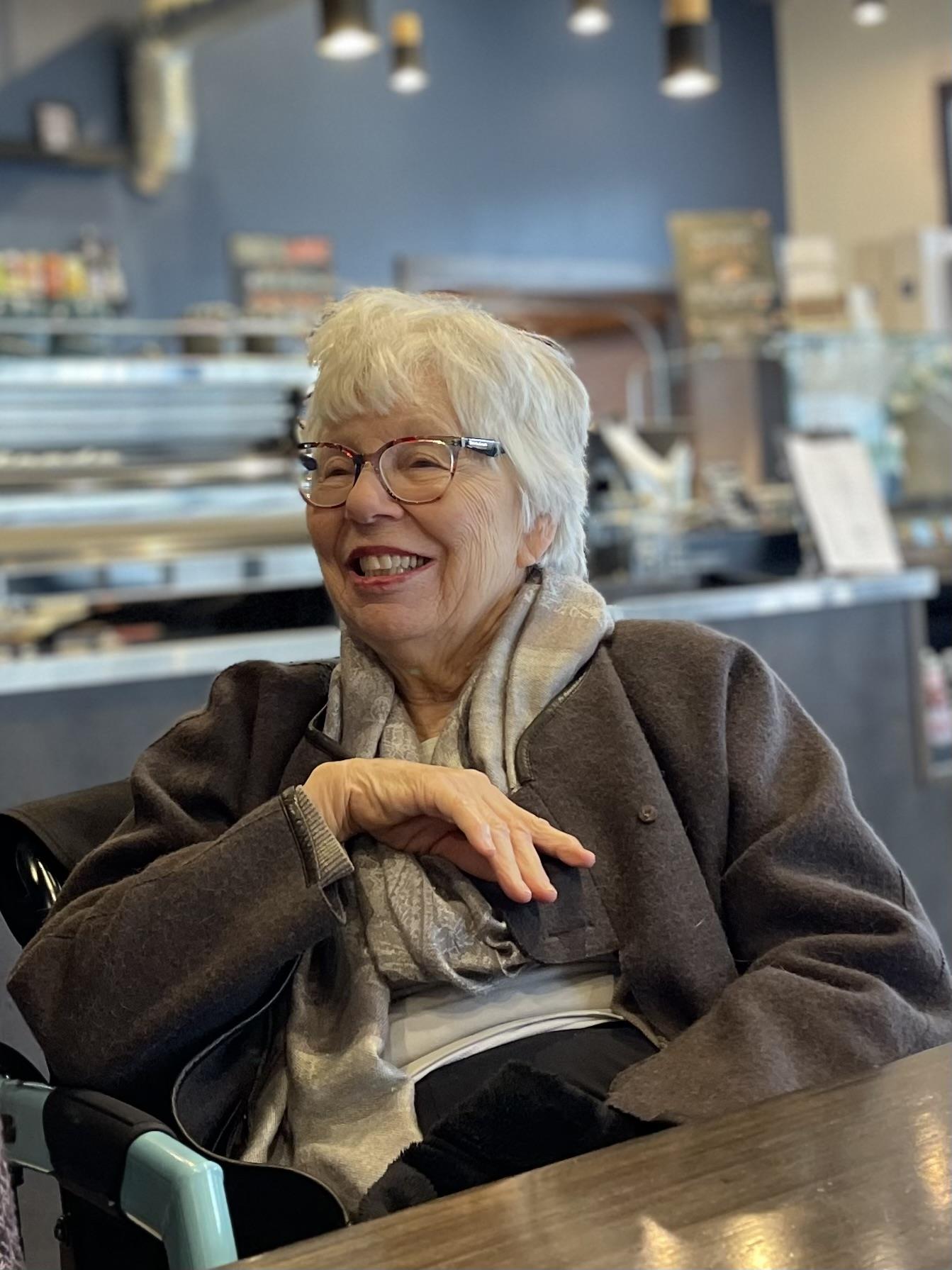 A cheerful woman enjoys her time in a café, sharing laughter and warmth with friends.