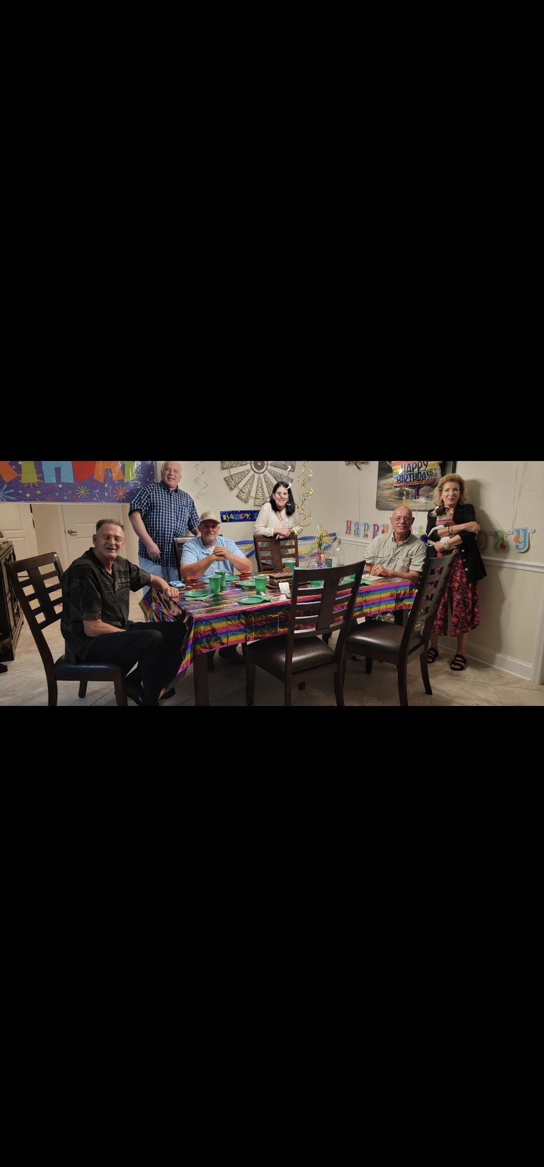 A joyful group enjoys a meal together around a vibrant table filled with dishes.