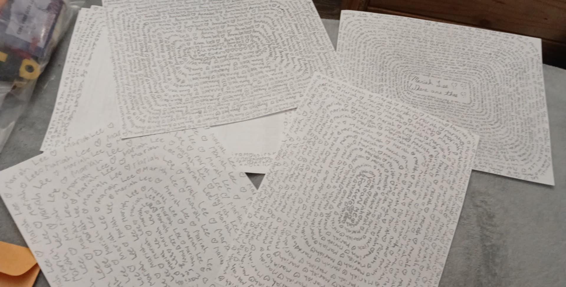 Handwritten notes resembling fingerprints are spread out on a table.