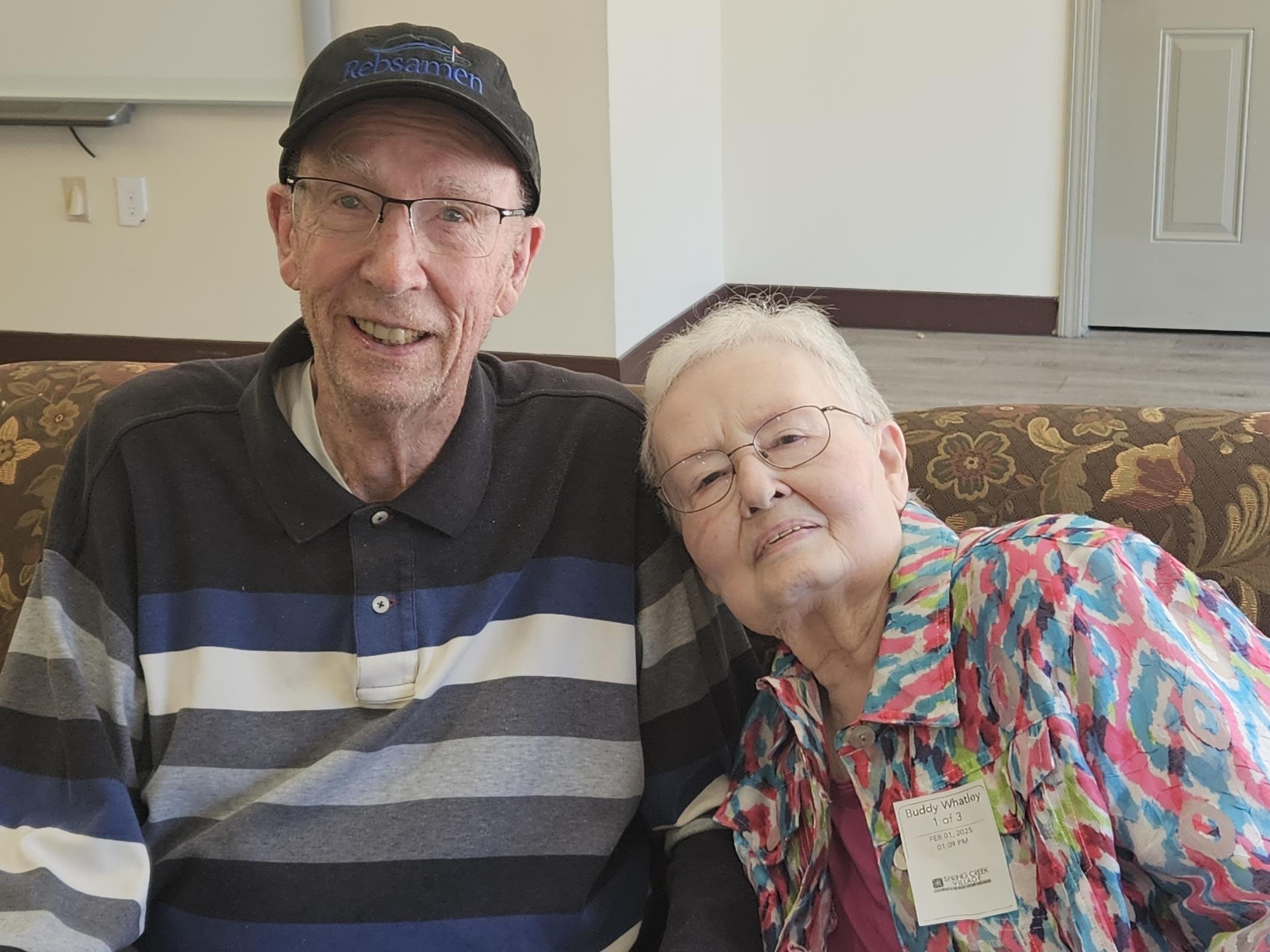 An elderly couple enjoys a joyful moment together in a warm, cozy setting.