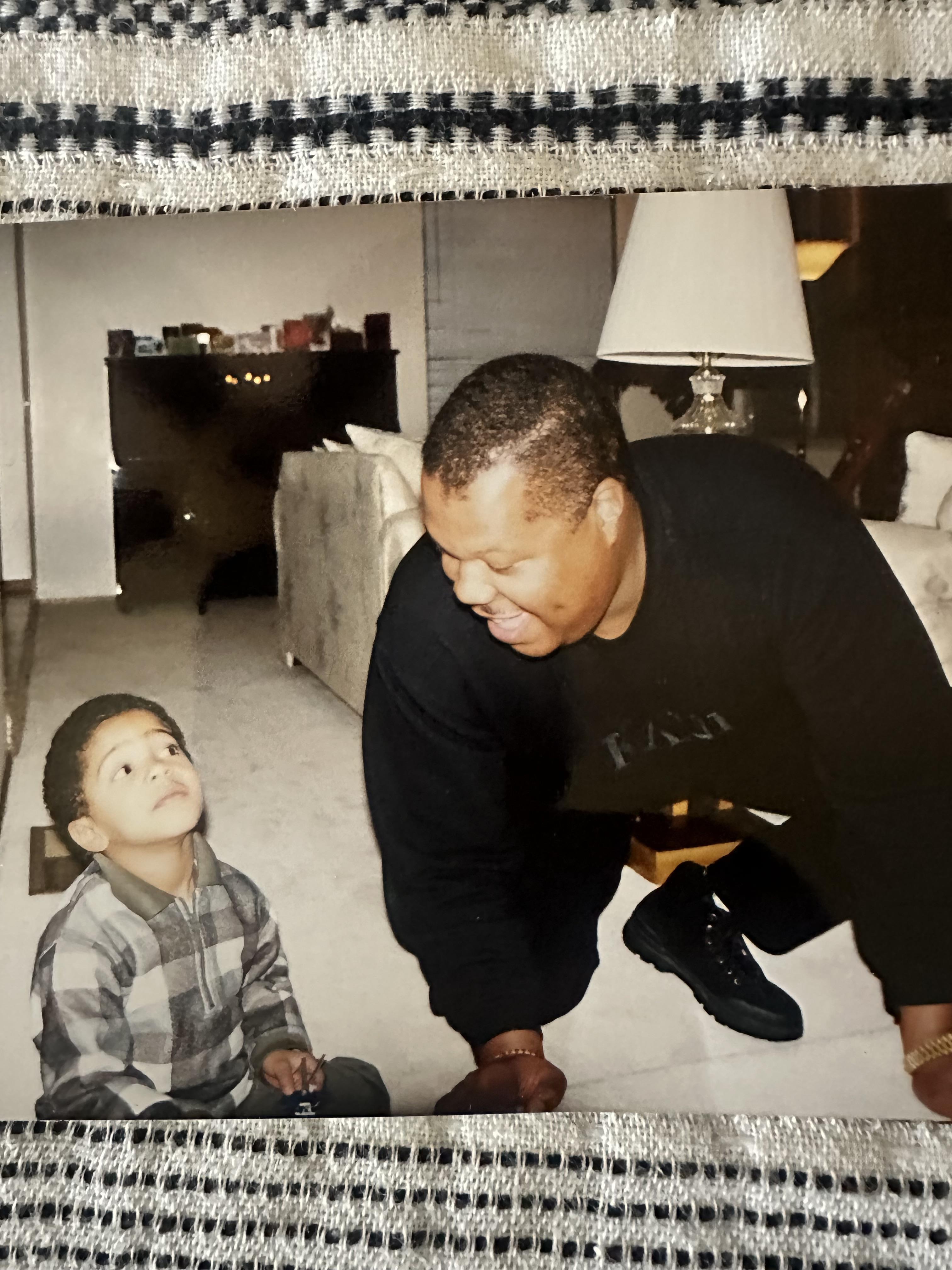 A father kneels on the floor, engaging playfully with his son in a cozy living room.