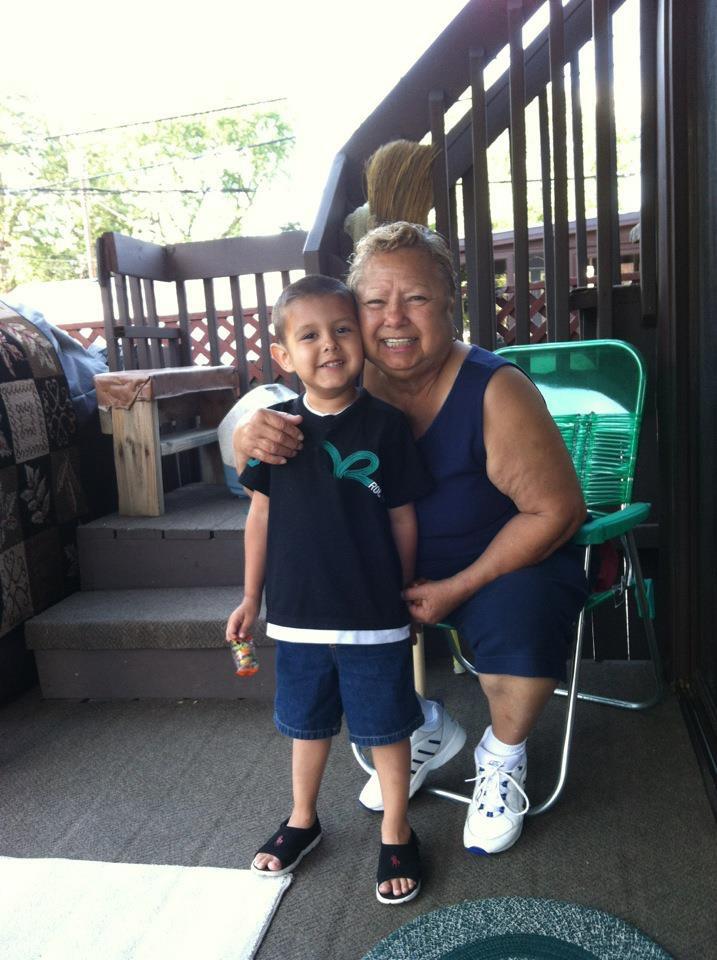 Grandmother and grandson share a joyful moment together in a backyard, smiling warmly.