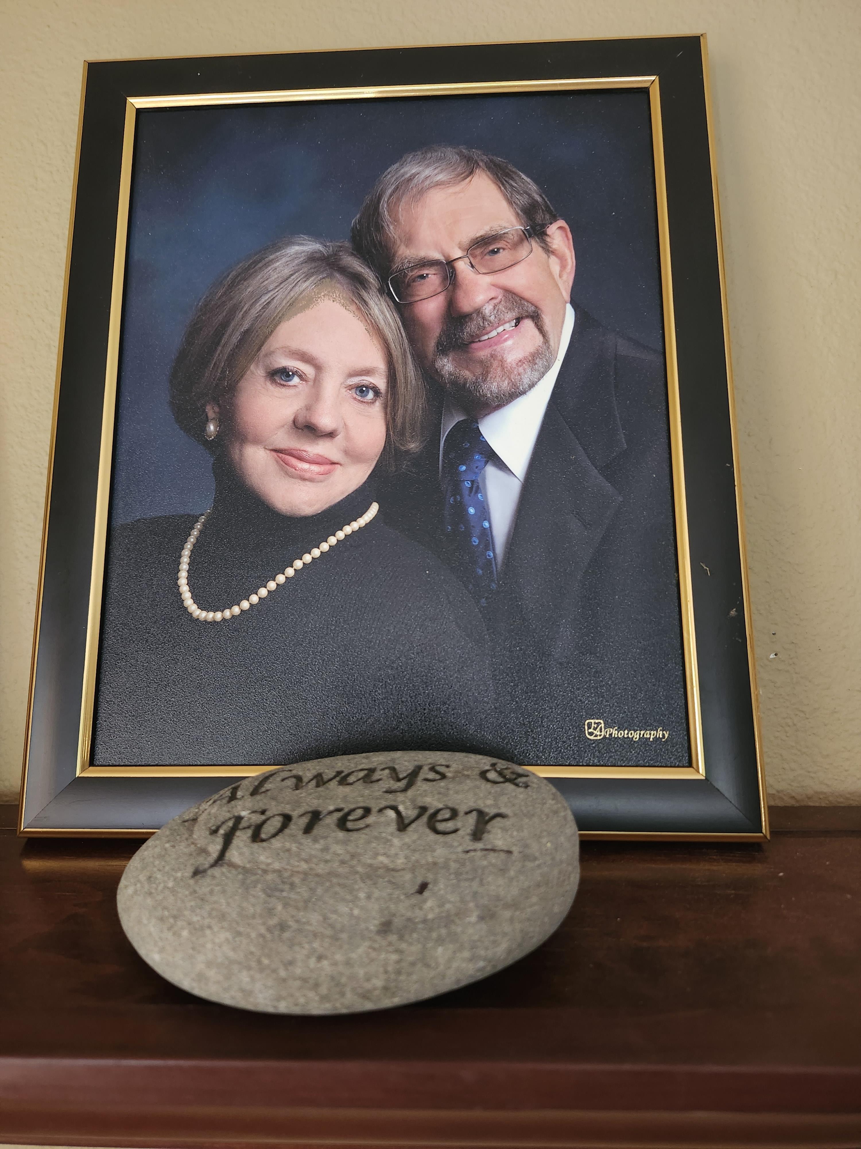 A framed portrait of a smiling couple sits by a stone etched with always and forever.