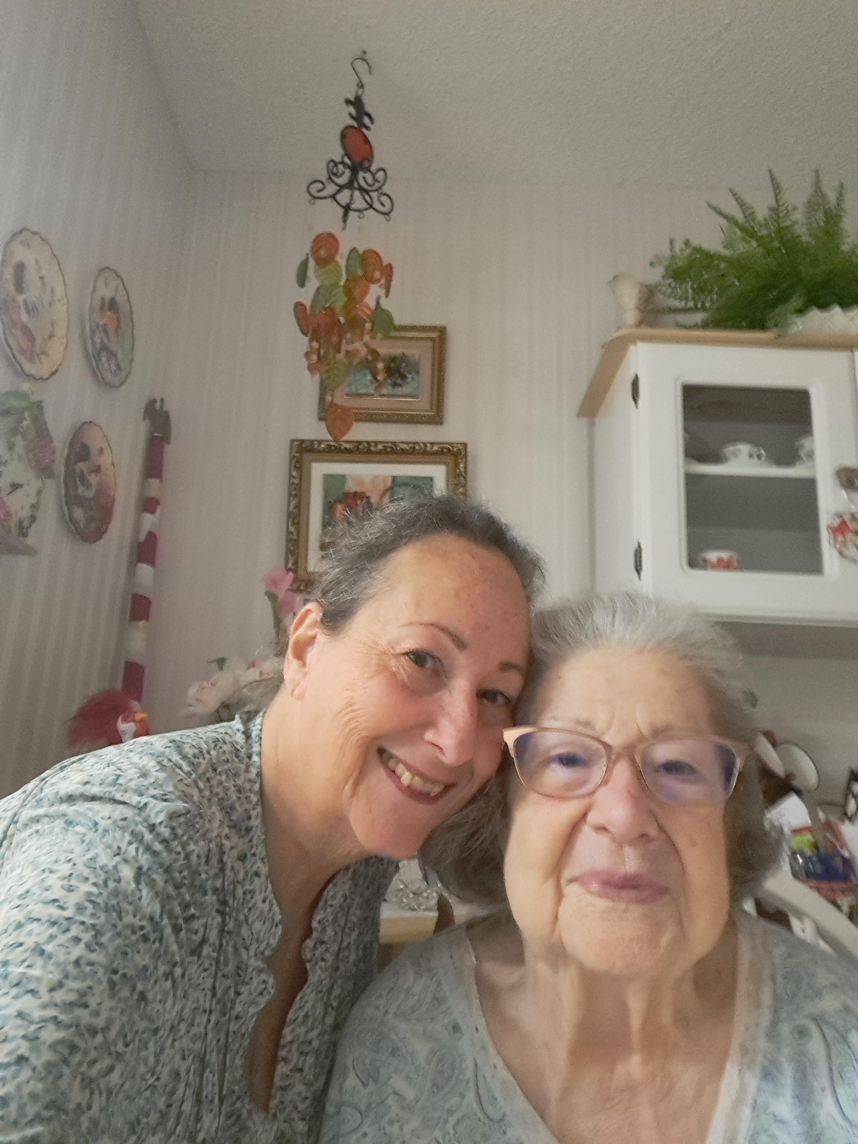 Two family members smile together in a warm kitchen full of decorations and memories.