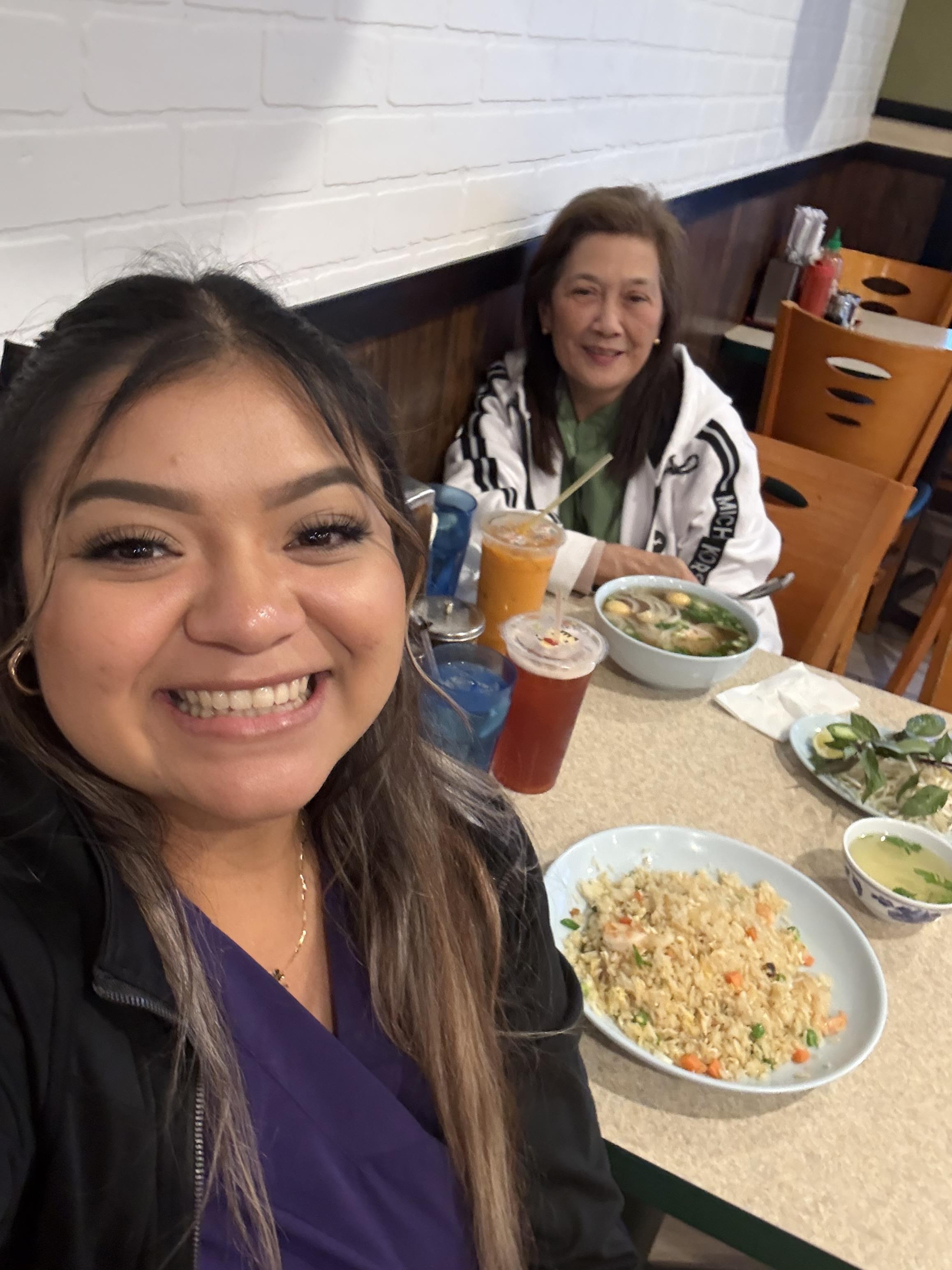Two friends enjoy their meal together, laughing and sharing moments at a bustling restaurant.