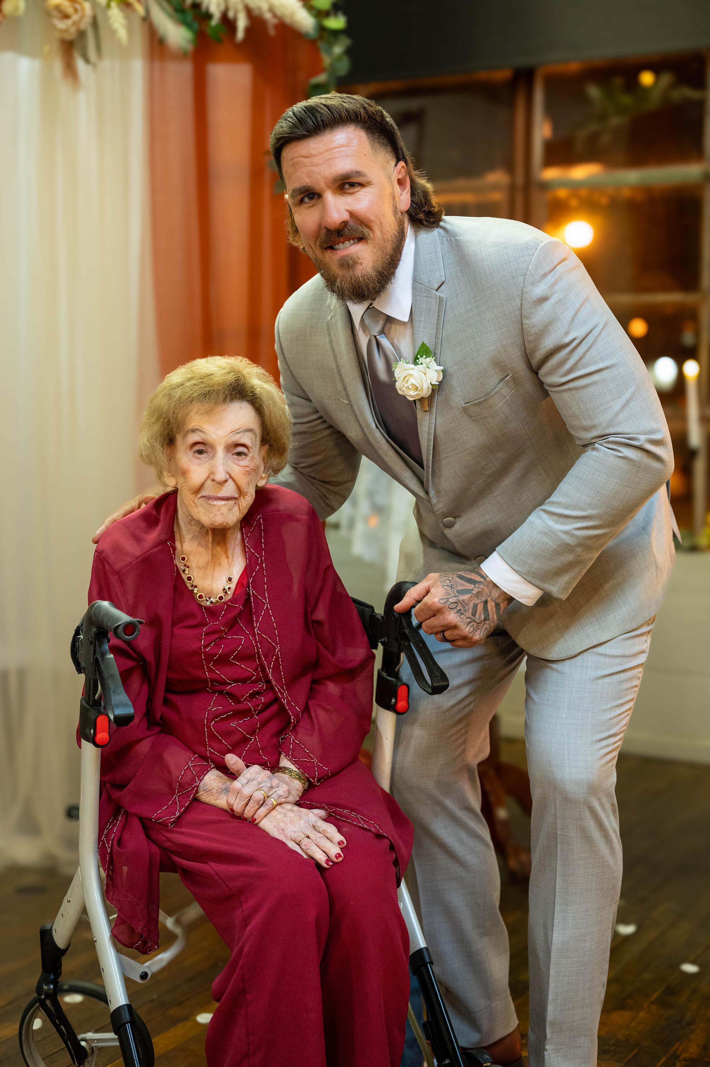 A senior woman in formal attire enjoys a joyful moment with a younger man at a festive event.