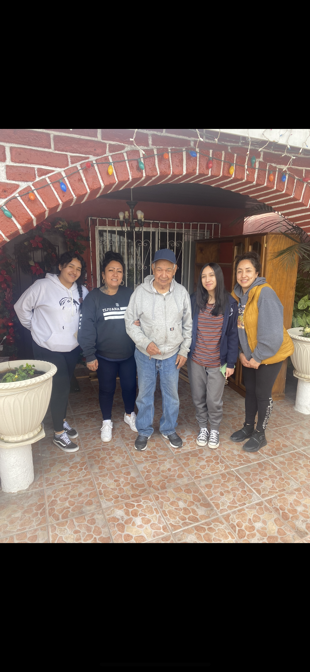 Five family members pose happily together in front of a charming home, sharing joyful moments.