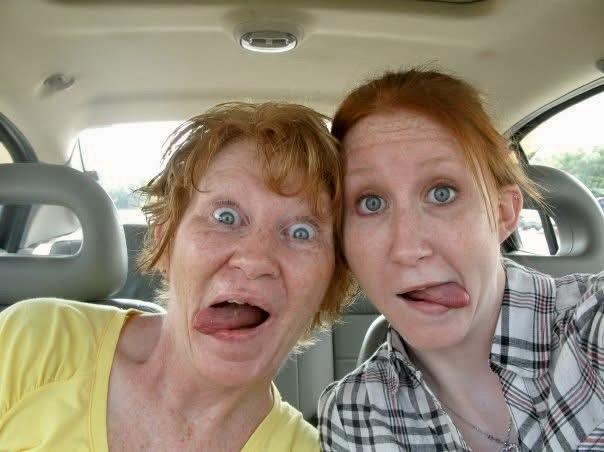 Two women show playful expressions while posing in a car, enjoying a fun moment together.