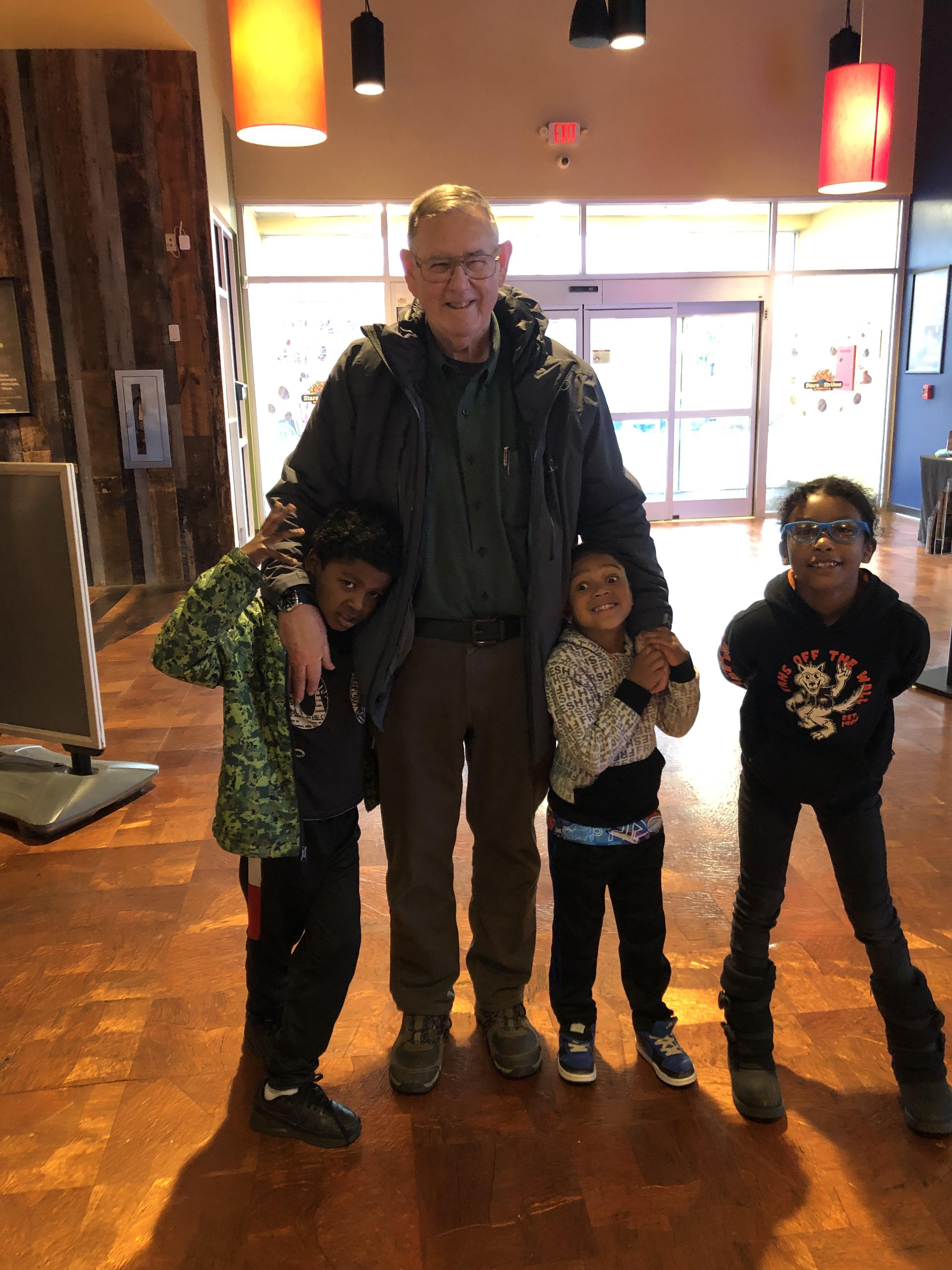 A man standing with his arms around a group of children