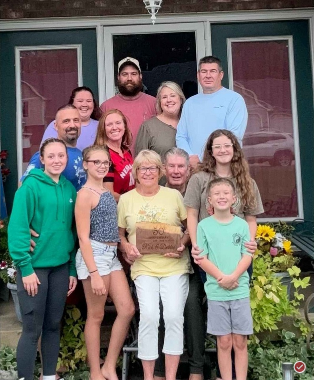 A large family is gathered on a porch, smiling and posing together for a group photo.