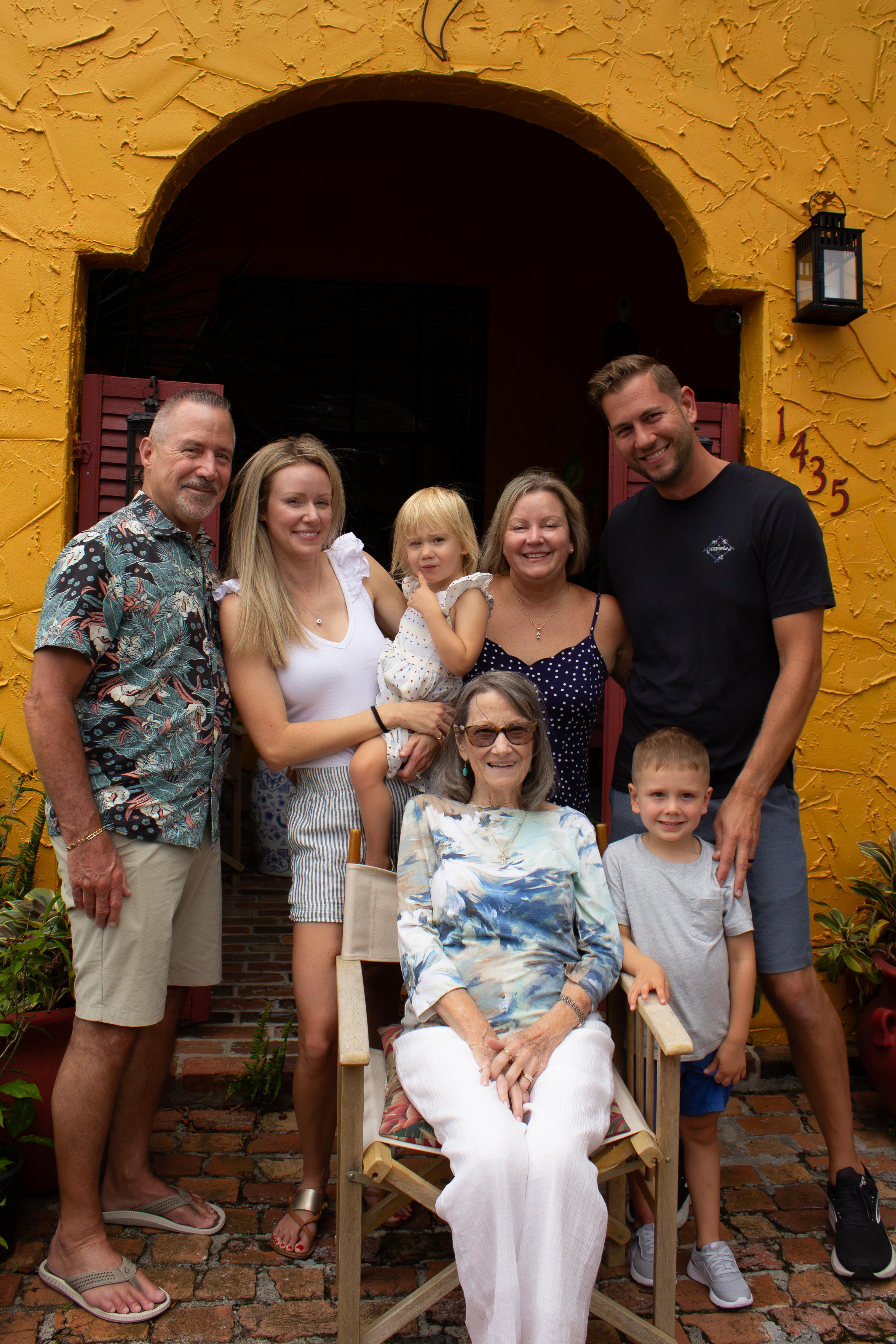 A happy family stands together in front of a bright yellow house, celebrating togetherness.