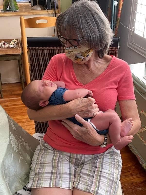 A loving grandmother gently holds her newborn grandchild in a warm, inviting space.
