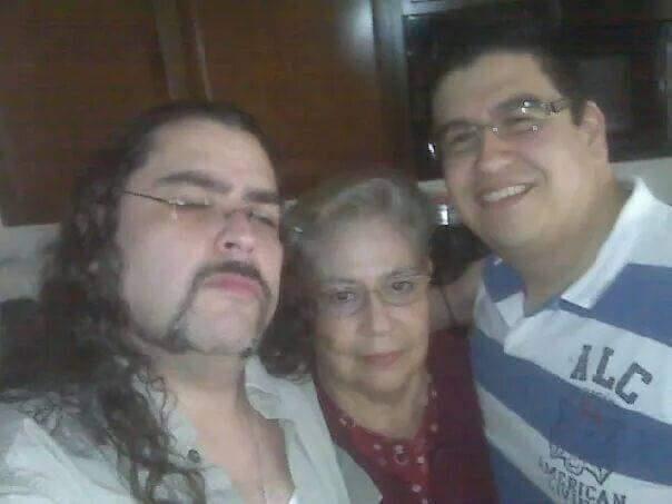 Three family members enjoy time together, smiling and posing indoors in a cozy setting.