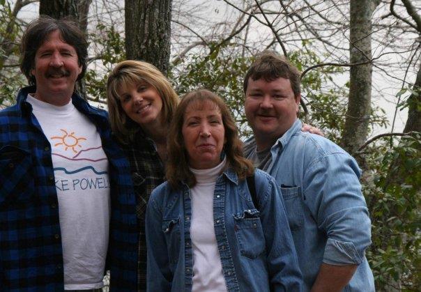 Four friends pose together in a forest, smiling and enjoying the outdoors during springtime.