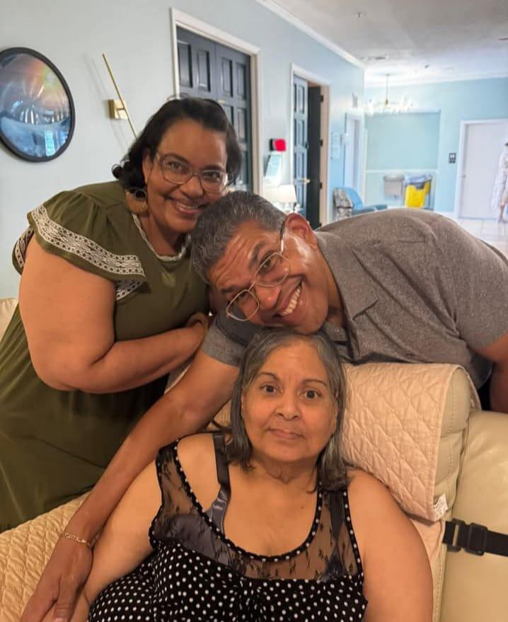 Three family members enjoy each other's company in a comfortable living space while laughing.