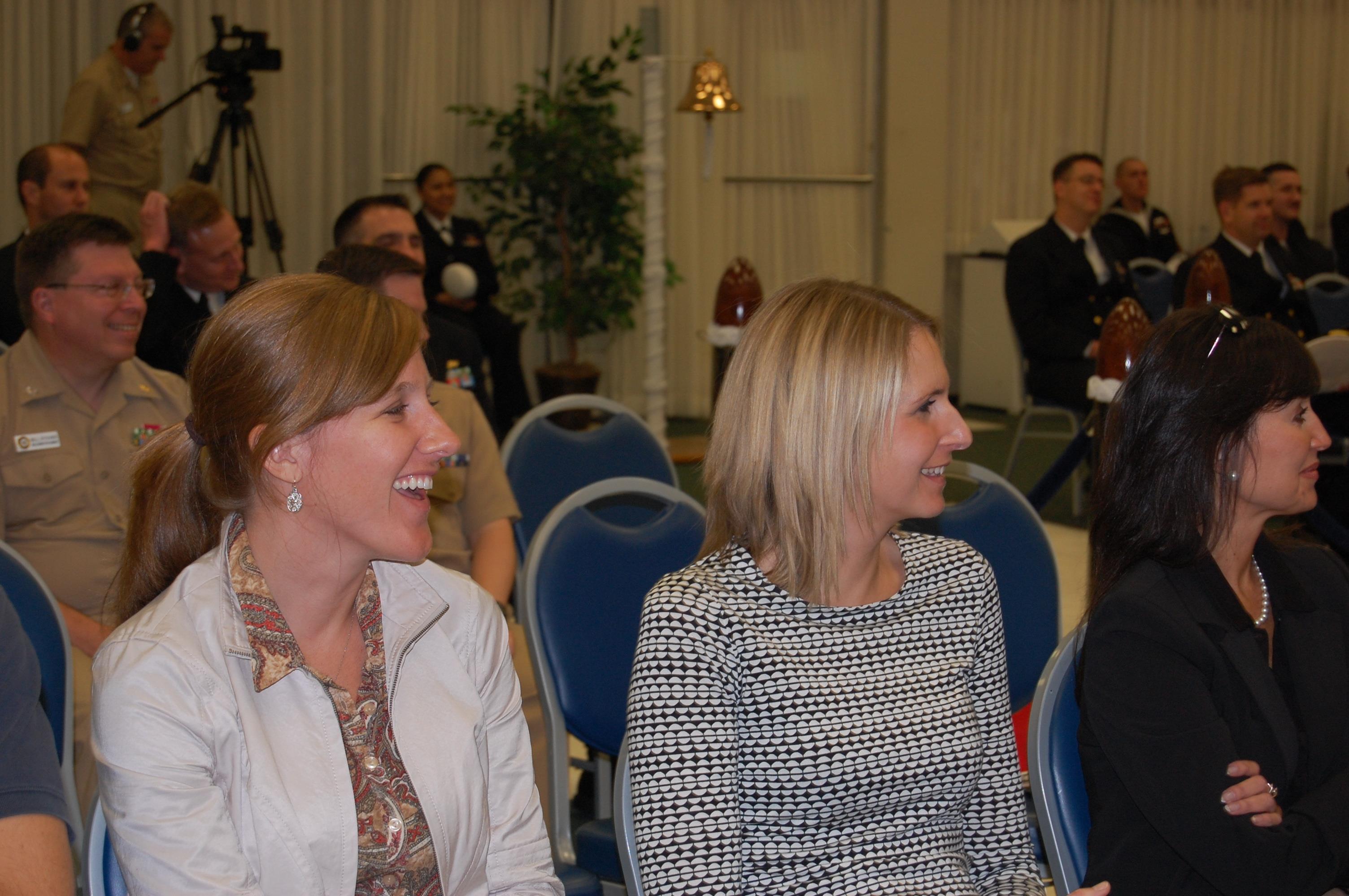 Participants are smiling and focused while attending a business presentation in a conference hall.