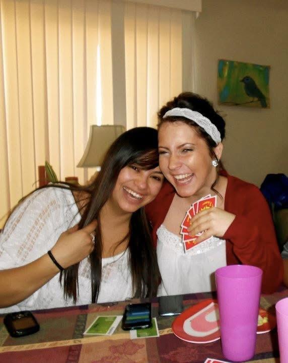 Two women share laughter and camaraderie while playing cards in a warm, inviting space.