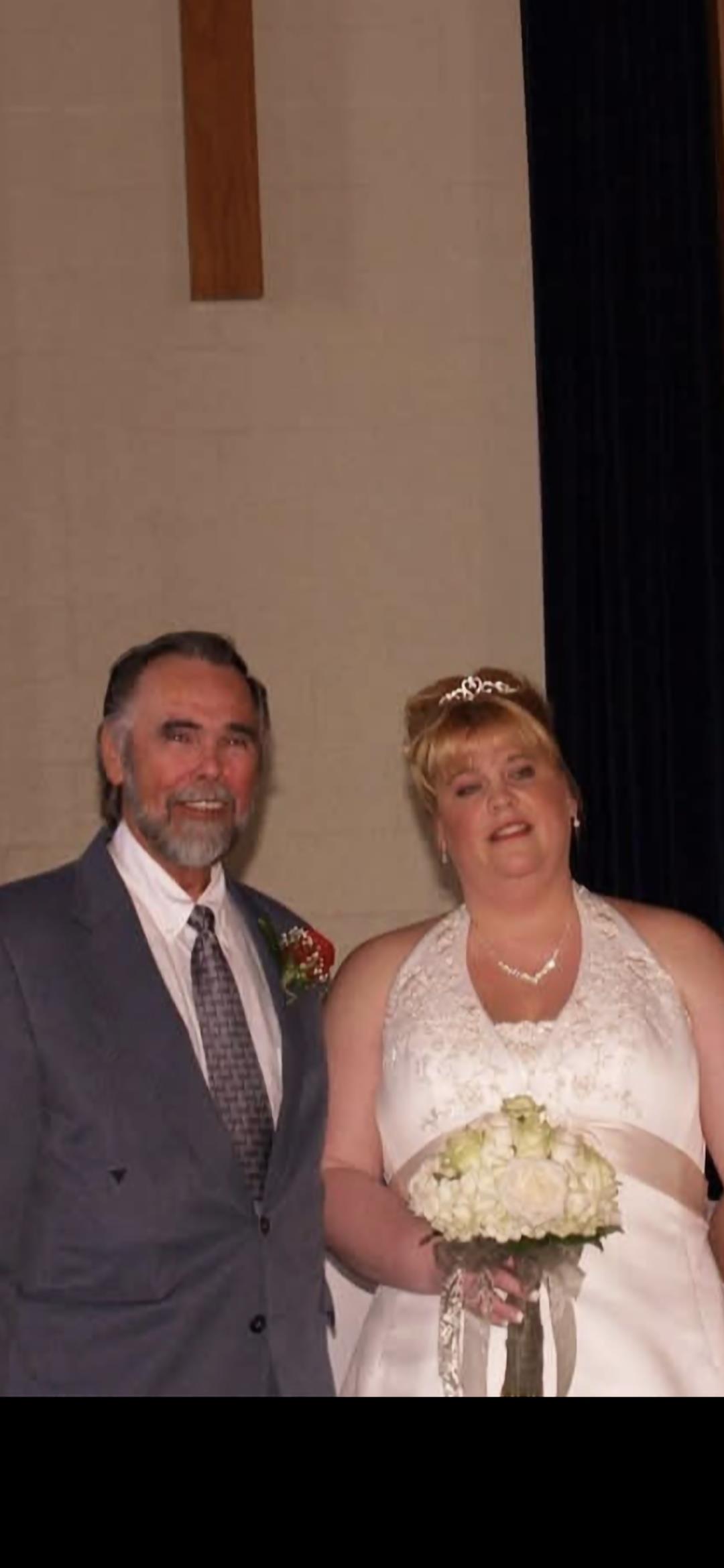 Smiling couple stands together in formal attire, celebrating their special day at a venue.