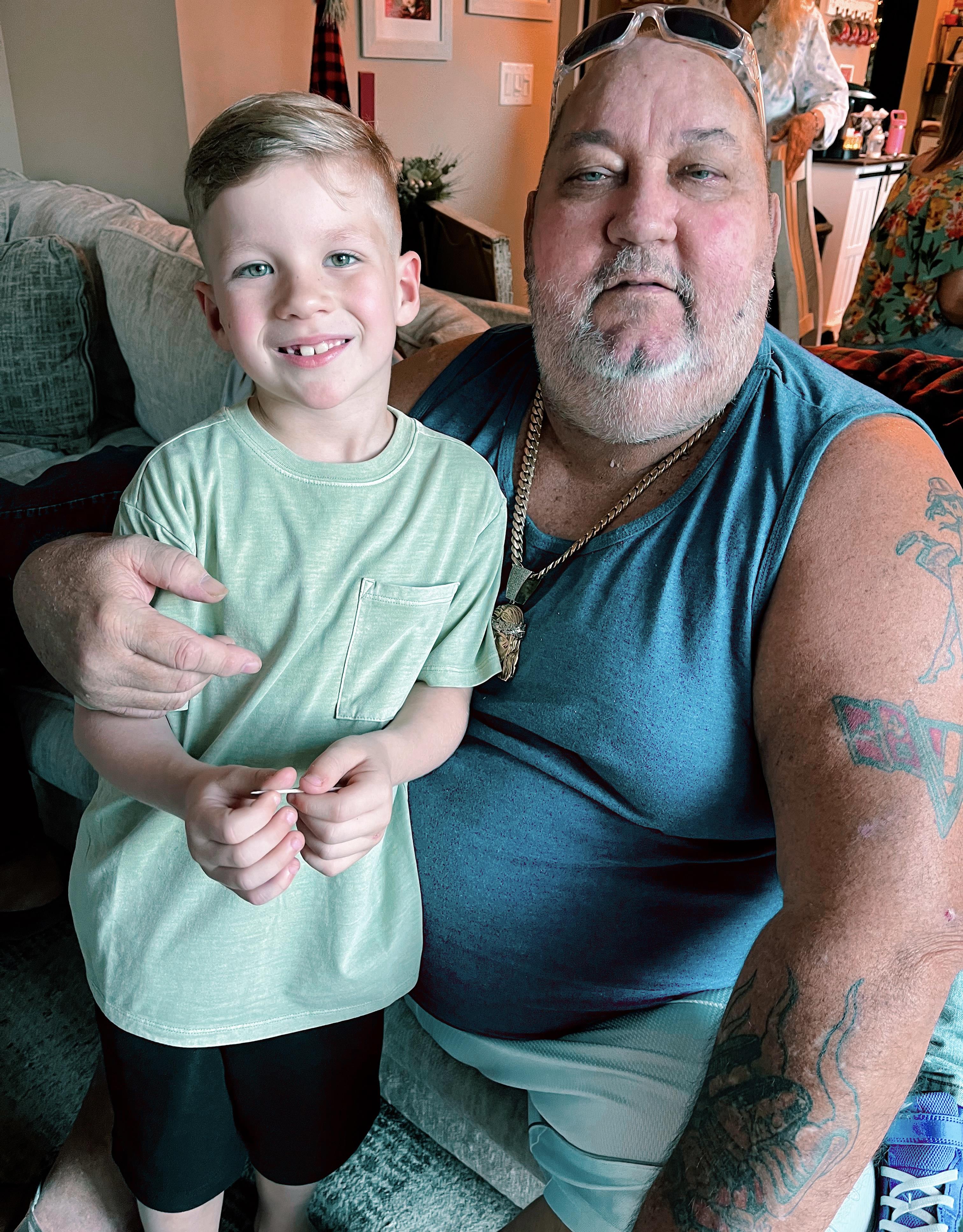 A smiling grandfather poses with his cheerful grandson, enjoying quality family time together.