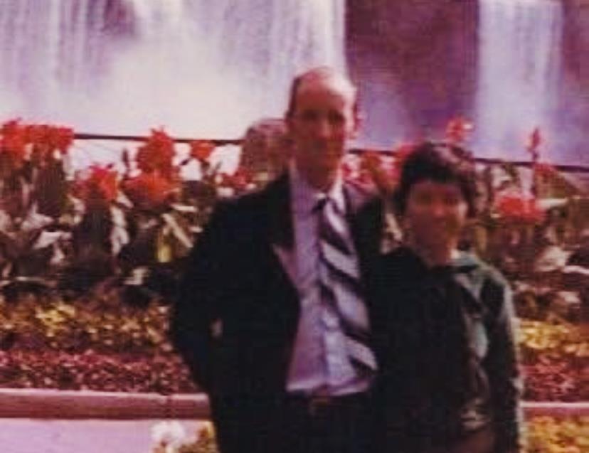 A couple enjoys a moment together by a lush flower garden and a flowing waterfall.