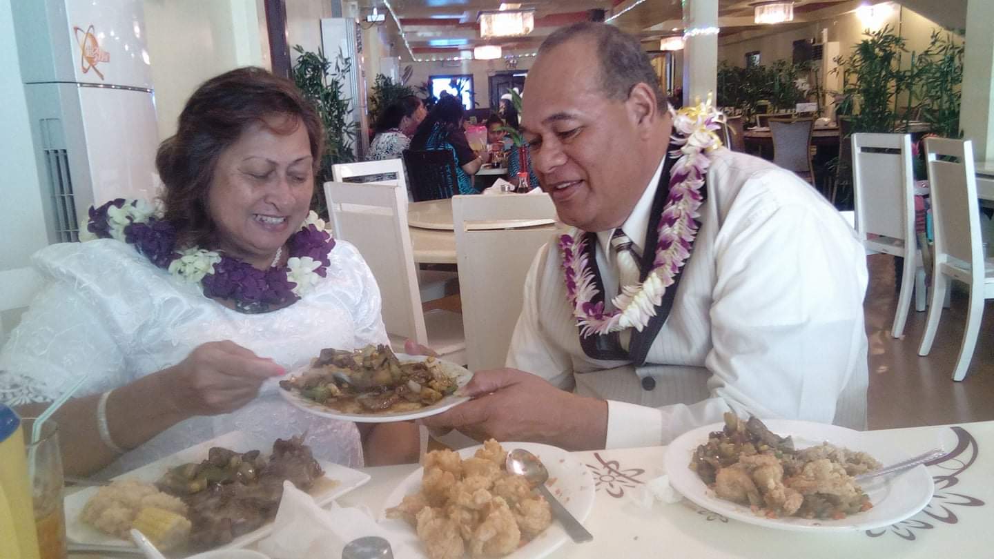 Two individuals share a plate of food, laughing and celebrating at a vibrant restaurant setting.