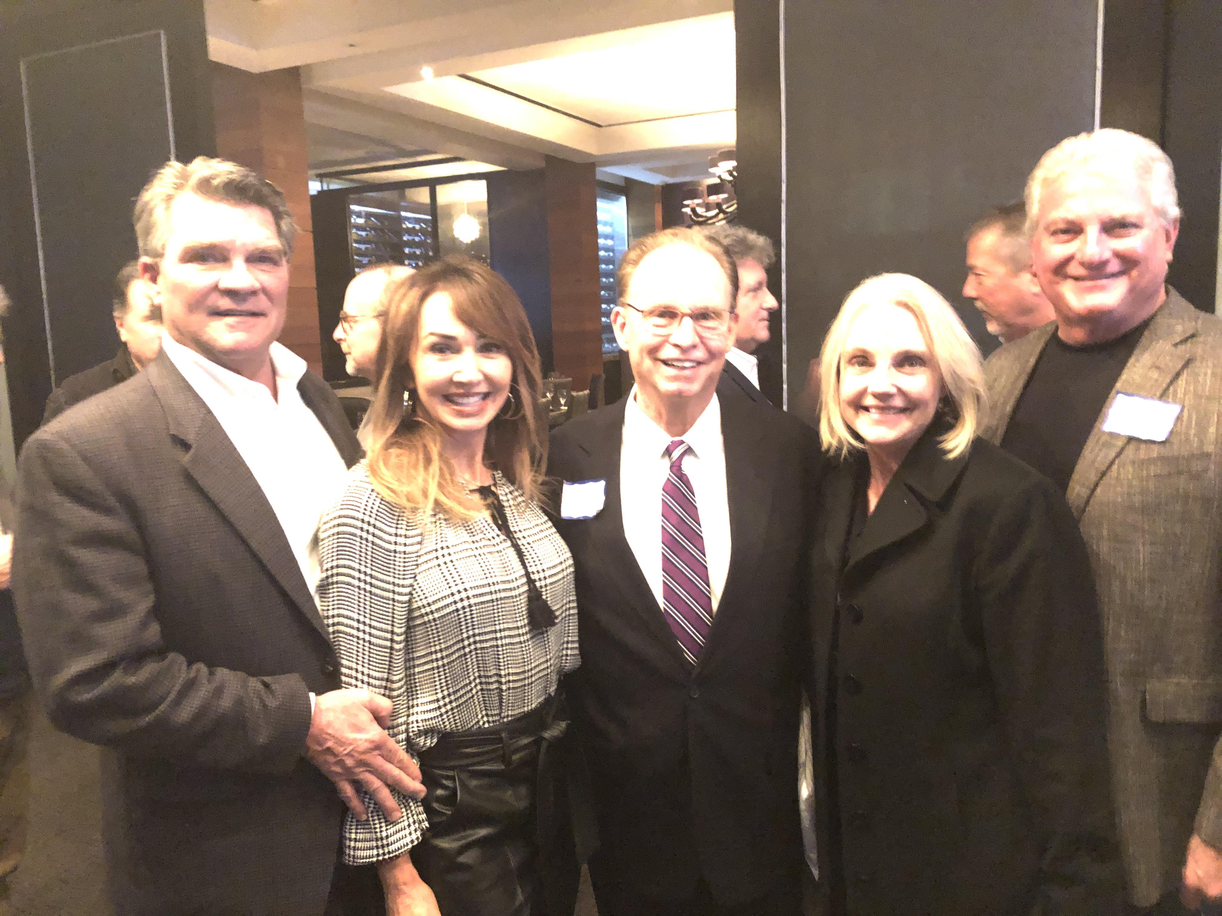 Friends mingle and enjoy conversation at a bustling restaurant event in the evening.