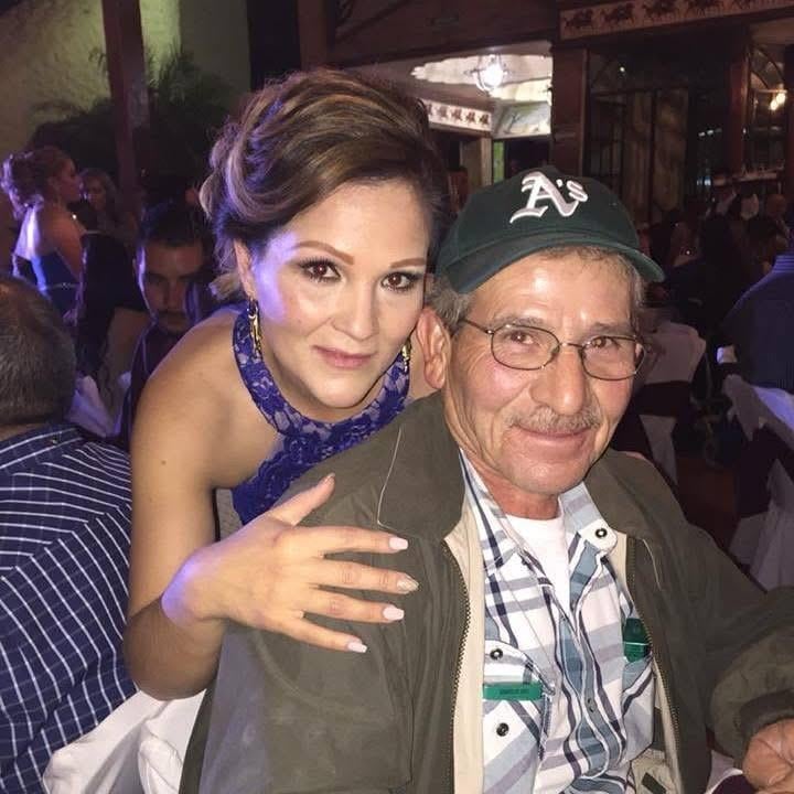 A woman in a blue dress smiles with an older man in a cap, enjoying the festive vibes.