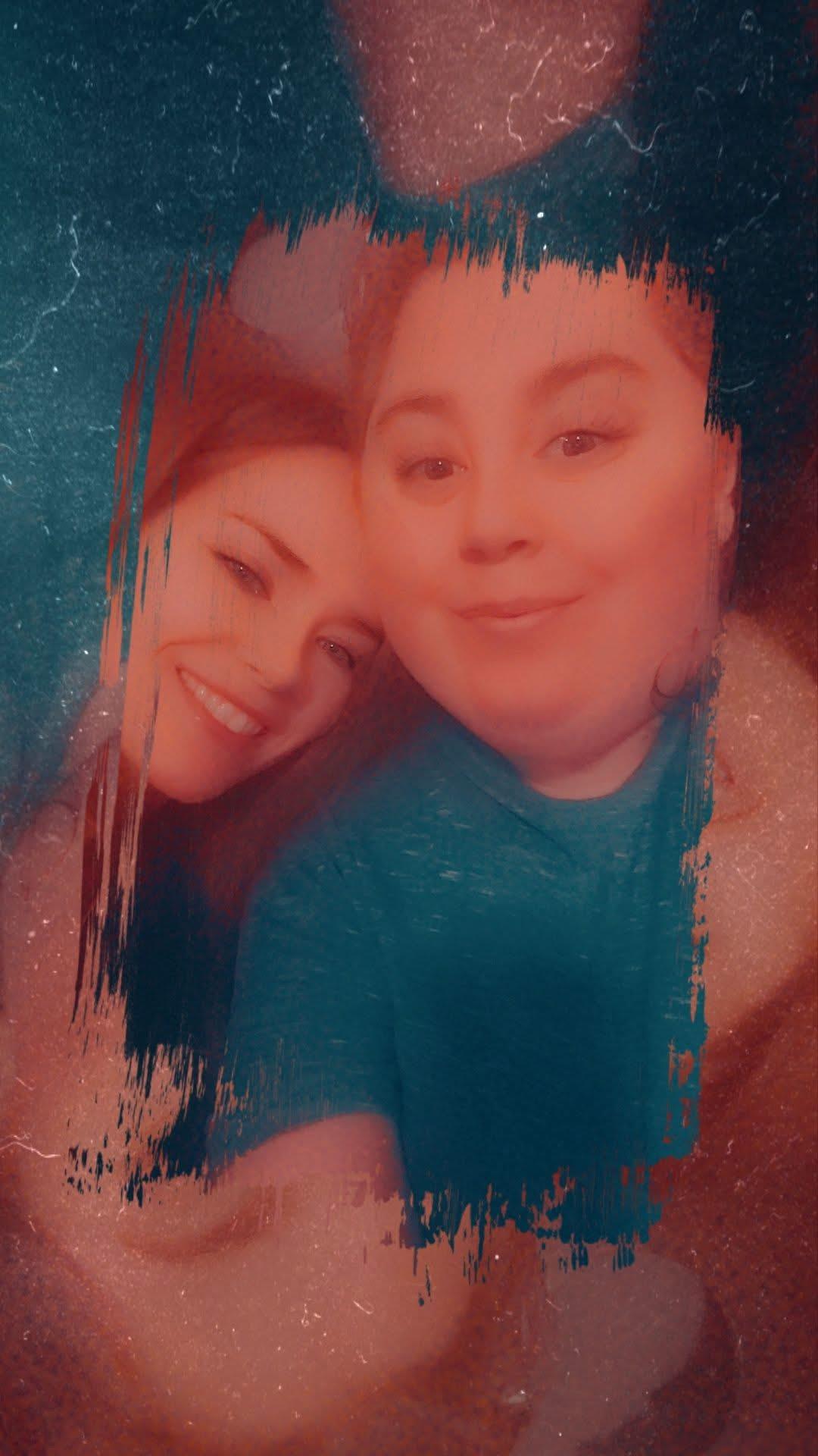 Two friends pose together, sharing smiles in a lively and colorful backdrop.