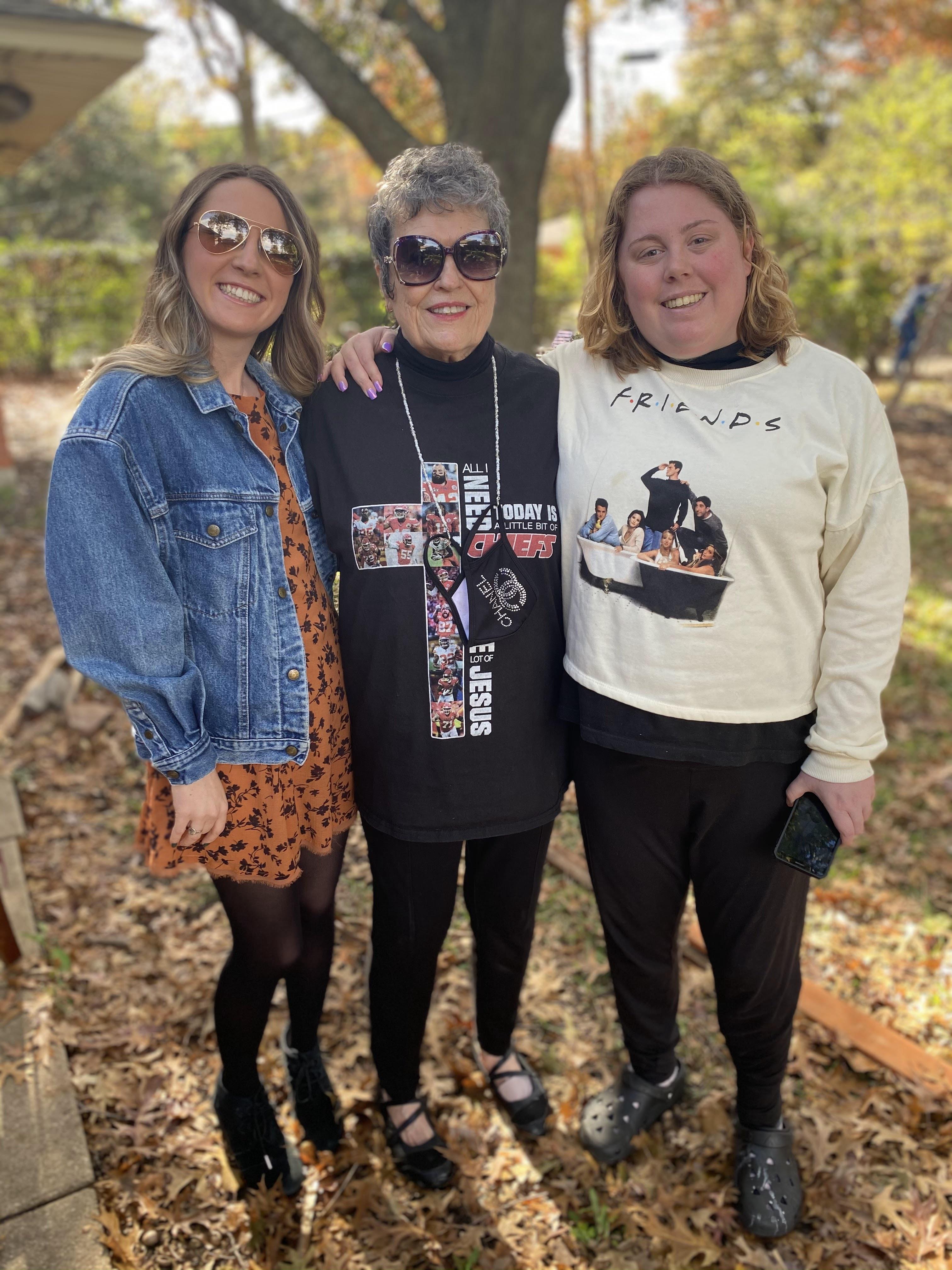 Three women pose together in a park, surrounded by autumn leaves and enjoying quality time.