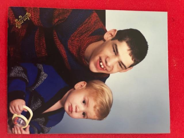 Two brothers, one older and one younger, share a lighthearted moment in cozy sweaters.