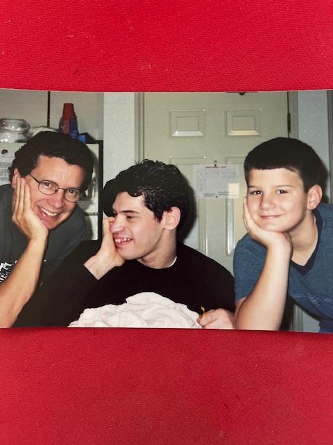 Three individuals share smiles and laughter, showcasing a lighthearted family moment at home.