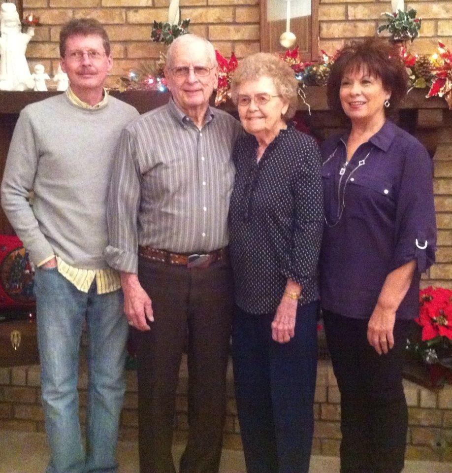 Family members stand together in front of a decorated fireplace during a holiday celebration.
