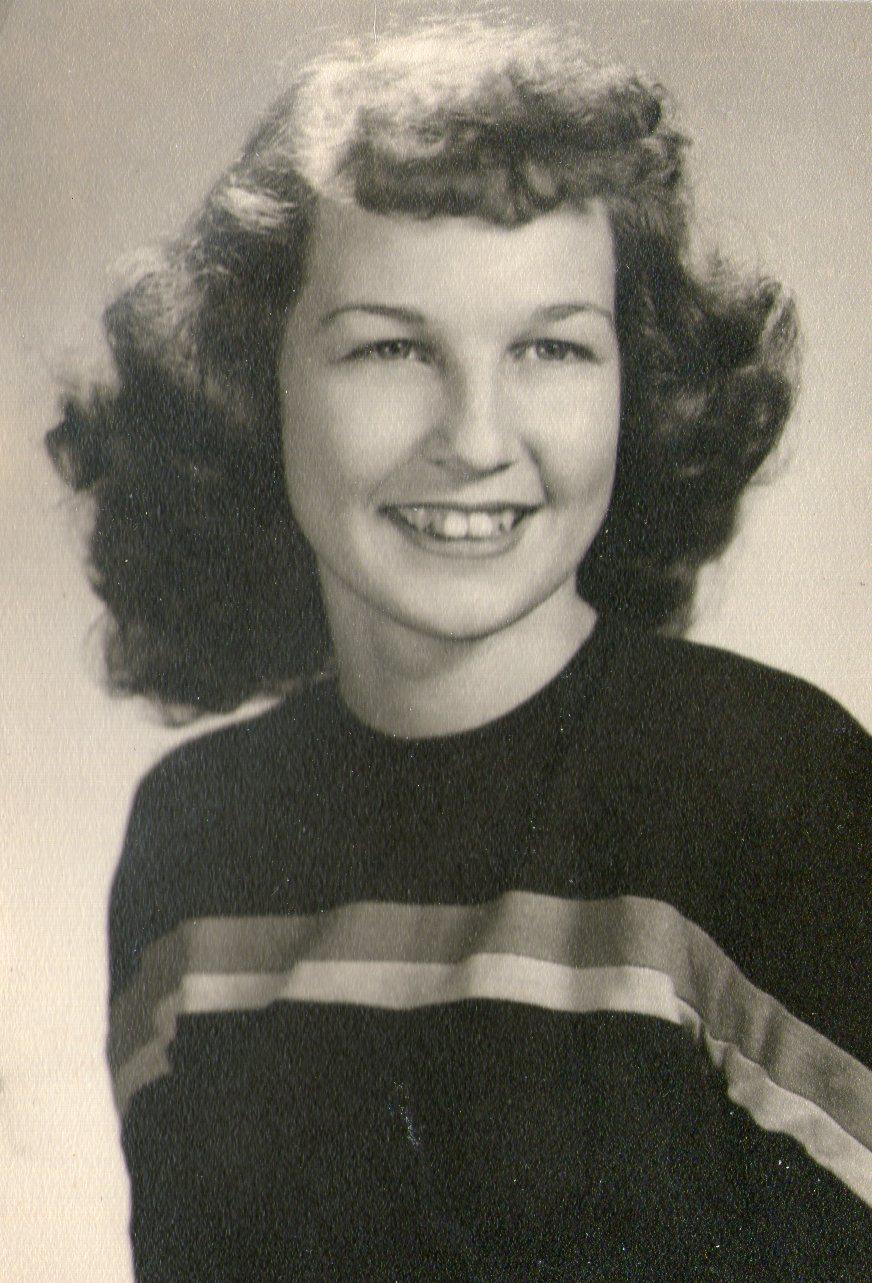 A young girl with curly hair smiles warmly, dressed in a stylish striped sweater.