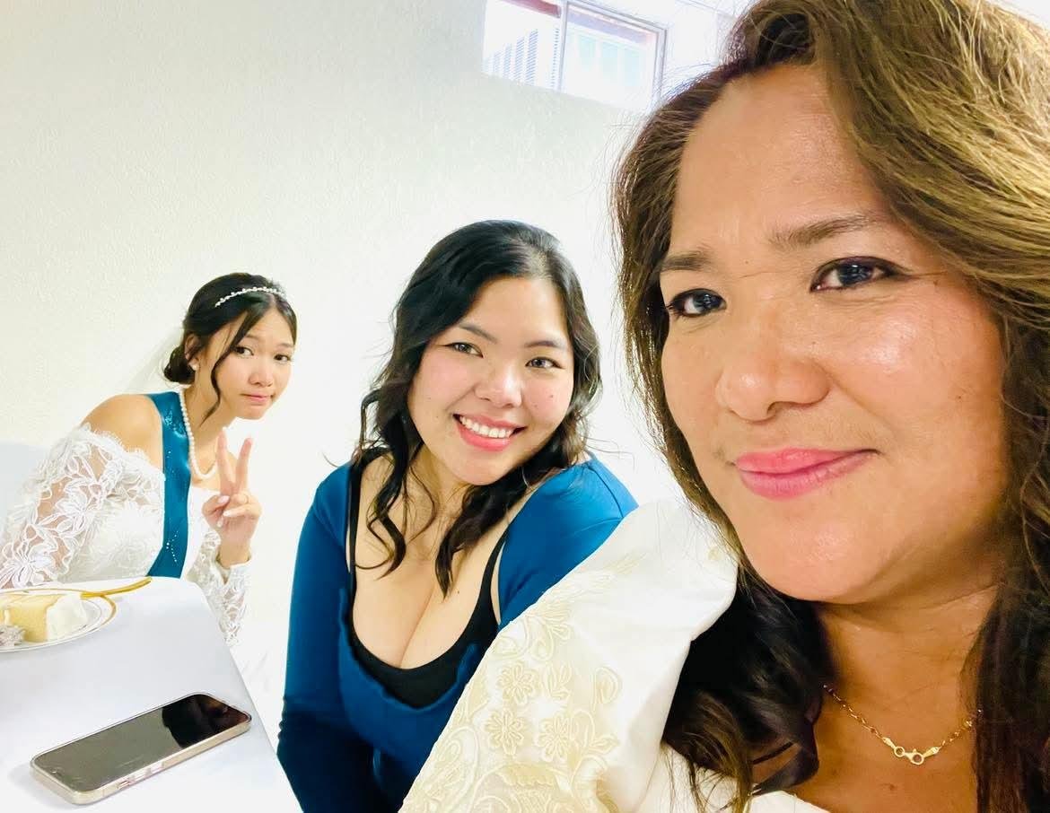 Three women happily pose together, celebrating their friendship at an indoor gathering.