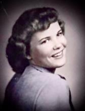 A joyful woman with classic hairstyle and outfit is smiling charmingly towards the camera.