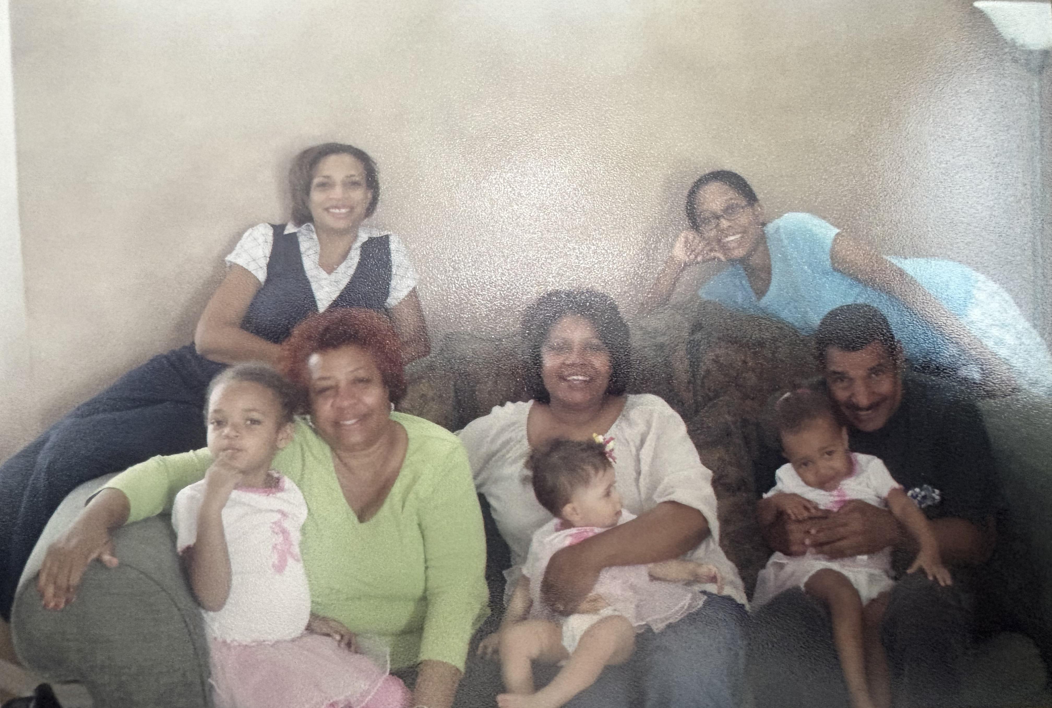 Several family members sit together in a cozy indoor space, laughing and bonding warmly.