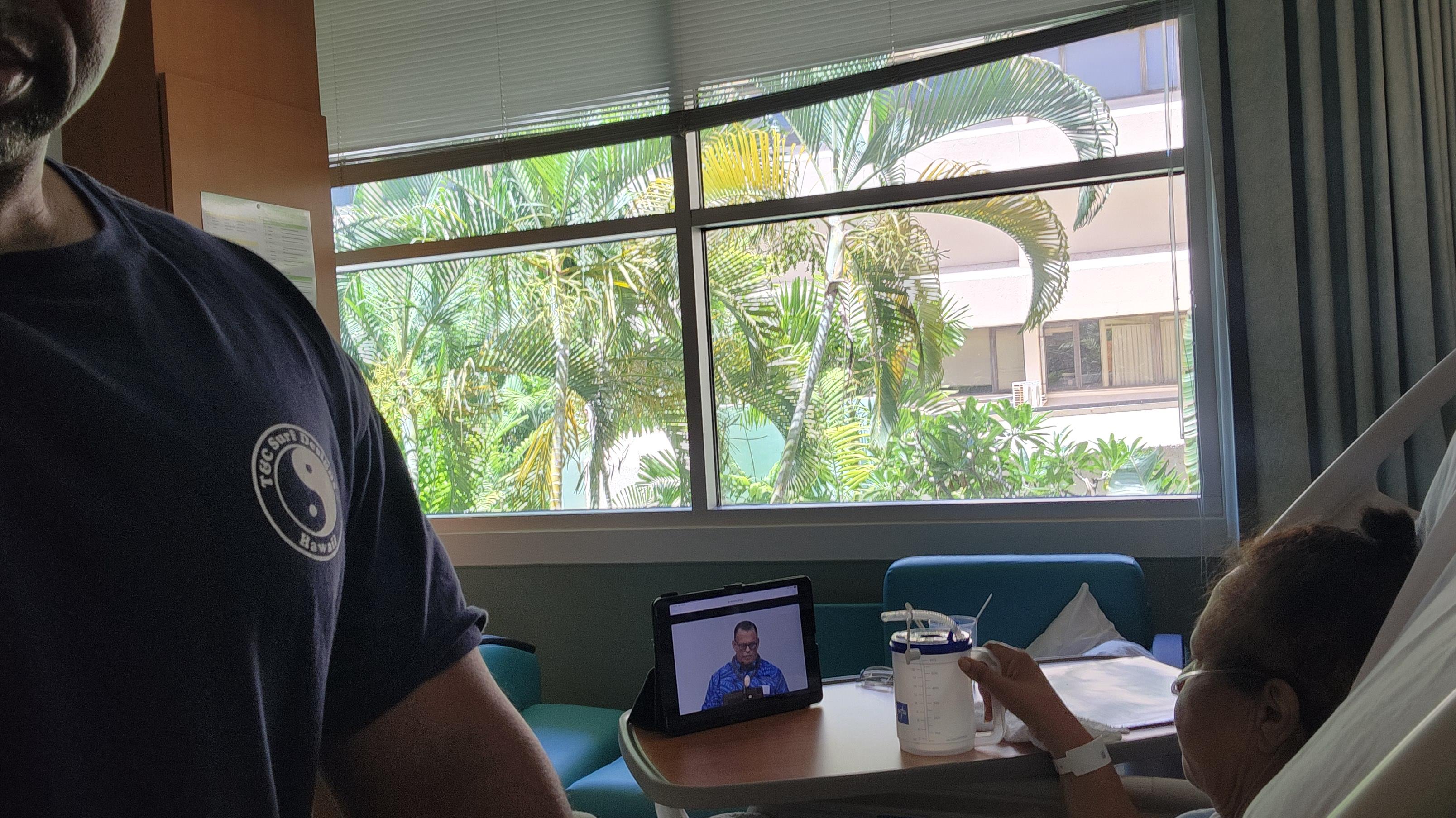 Participants engage in an indoor discussion while following a virtual meeting on a tablet.