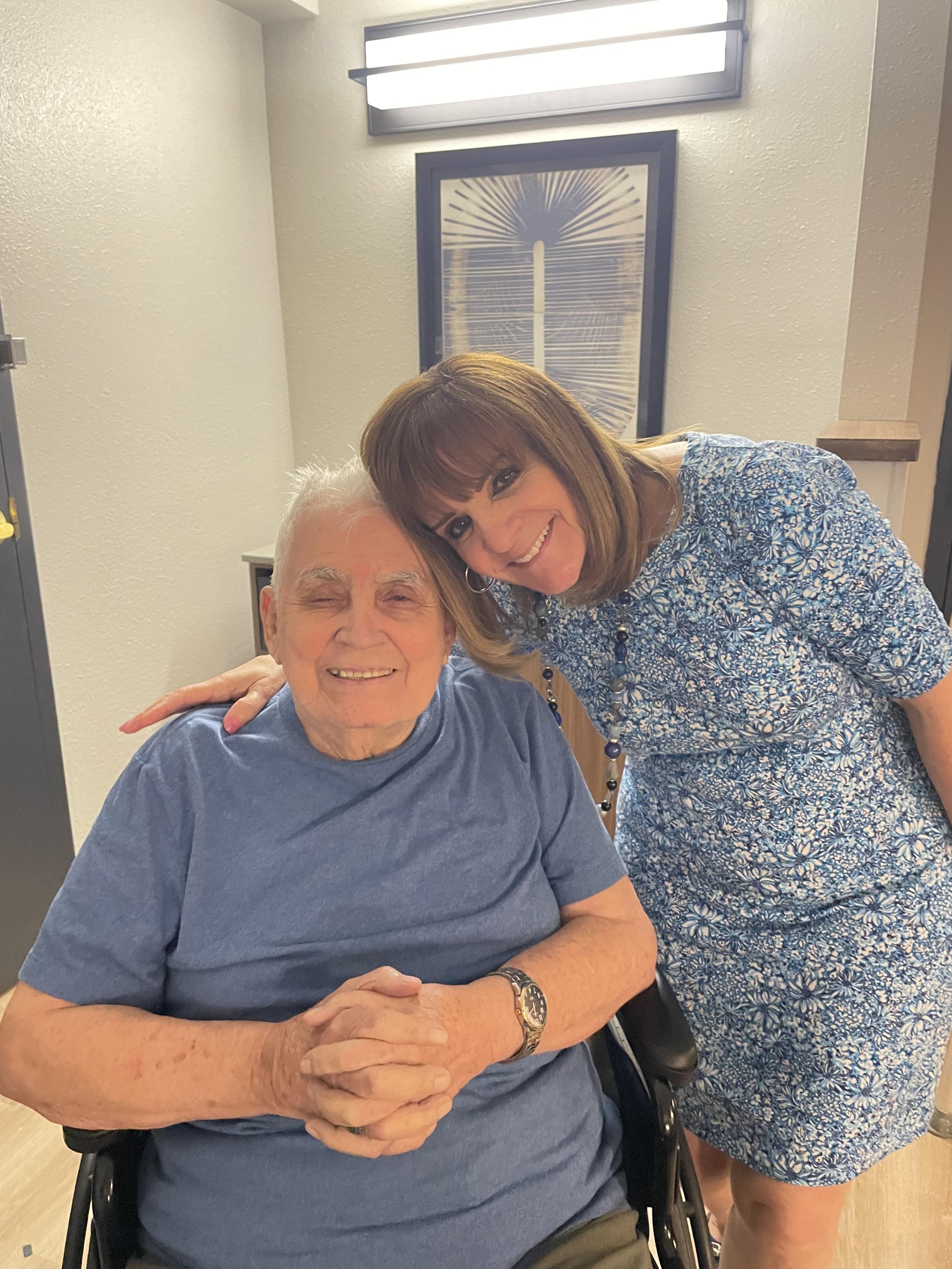 A caring caregiver shares a joyful moment with an elderly man in a warm setting.