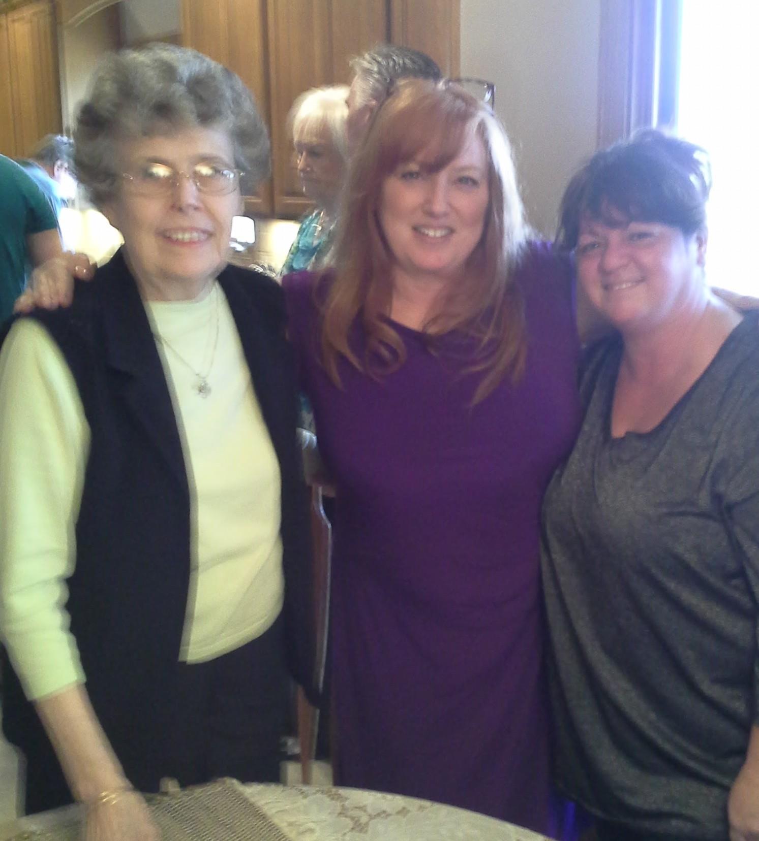 Three women enjoy each other's company at a friendly gathering in a cozy setting.