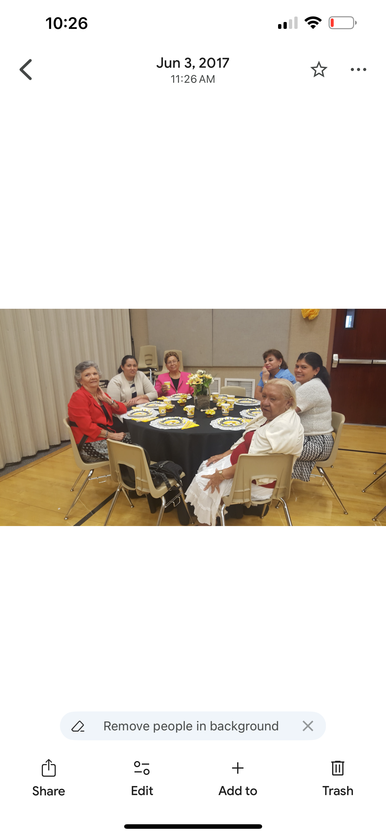 A group of six women enjoy each other's company at a decorated table during a community celebration.