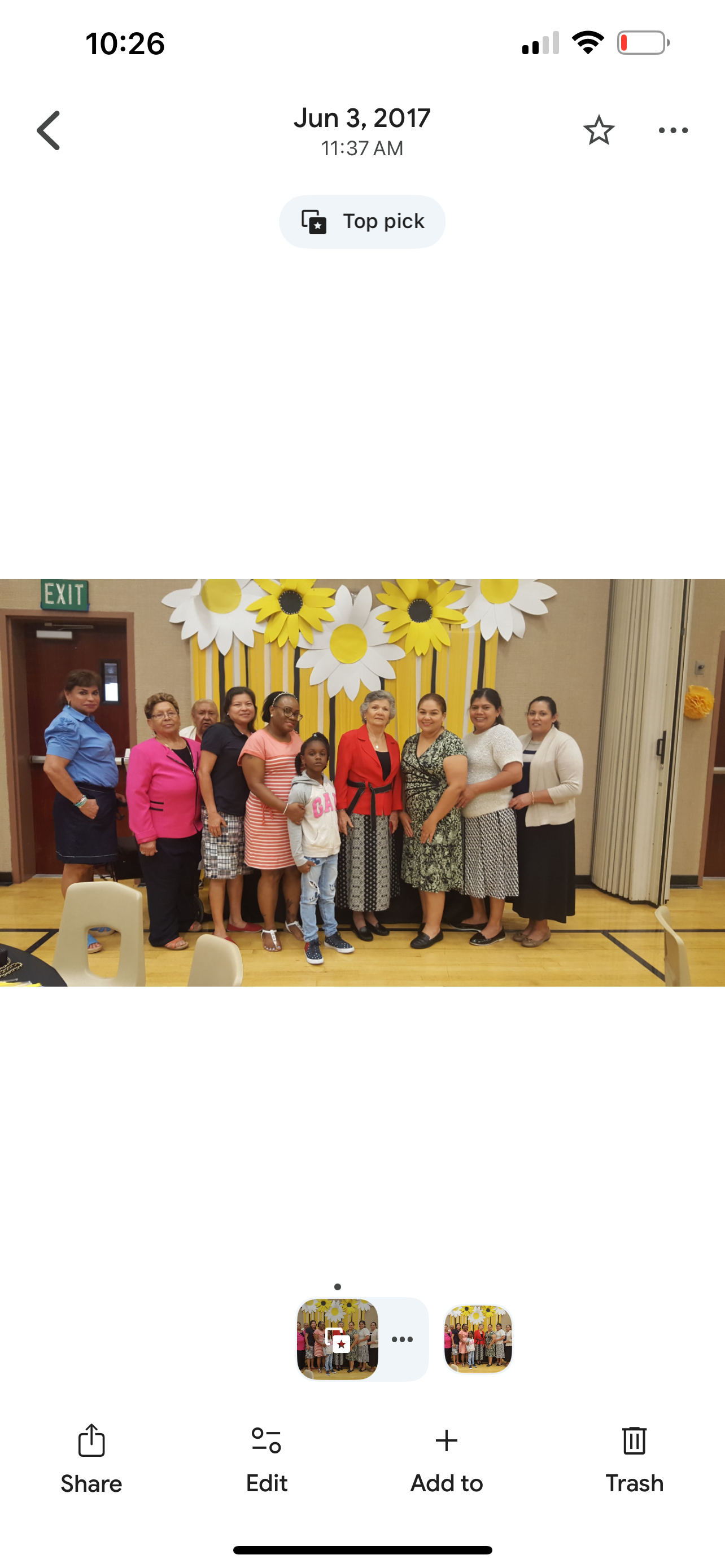 A group gathers together at a community event, smiling in front of vibrant floral decorations.