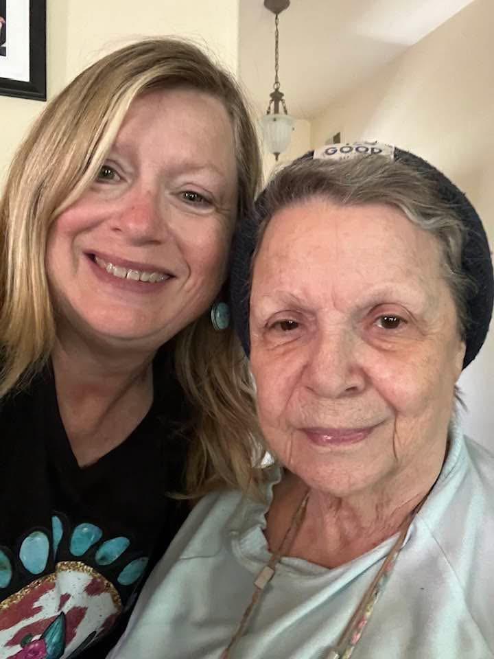 Two women share a joyful moment together in a welcoming home environment, smiling warmly.