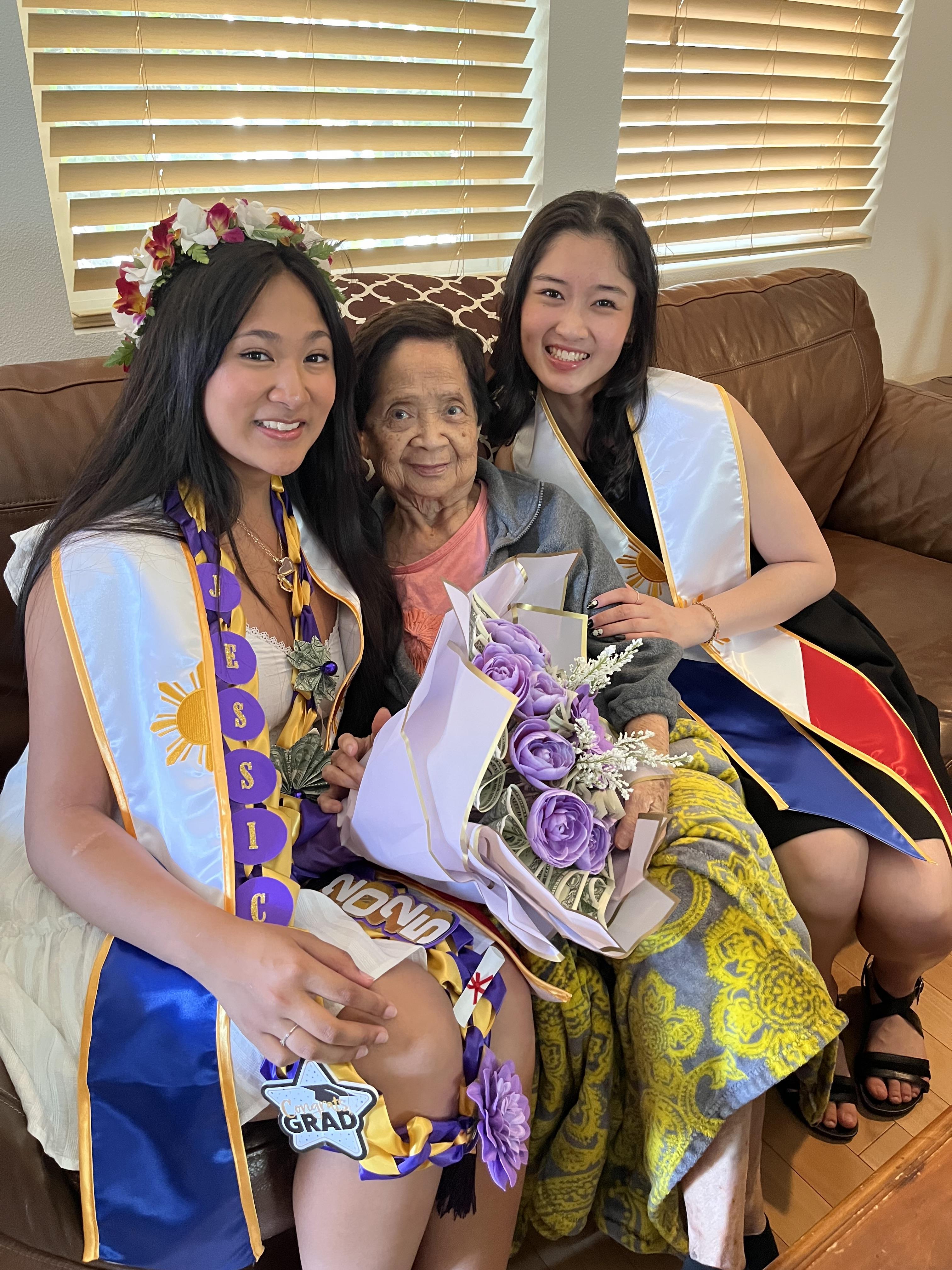 Two women in traditional dress pose with their grandmother, highlighting family love.