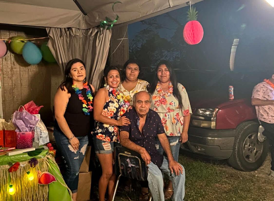 Family members enjoy a joyful gathering at night decorated with colorful lights and flowers.