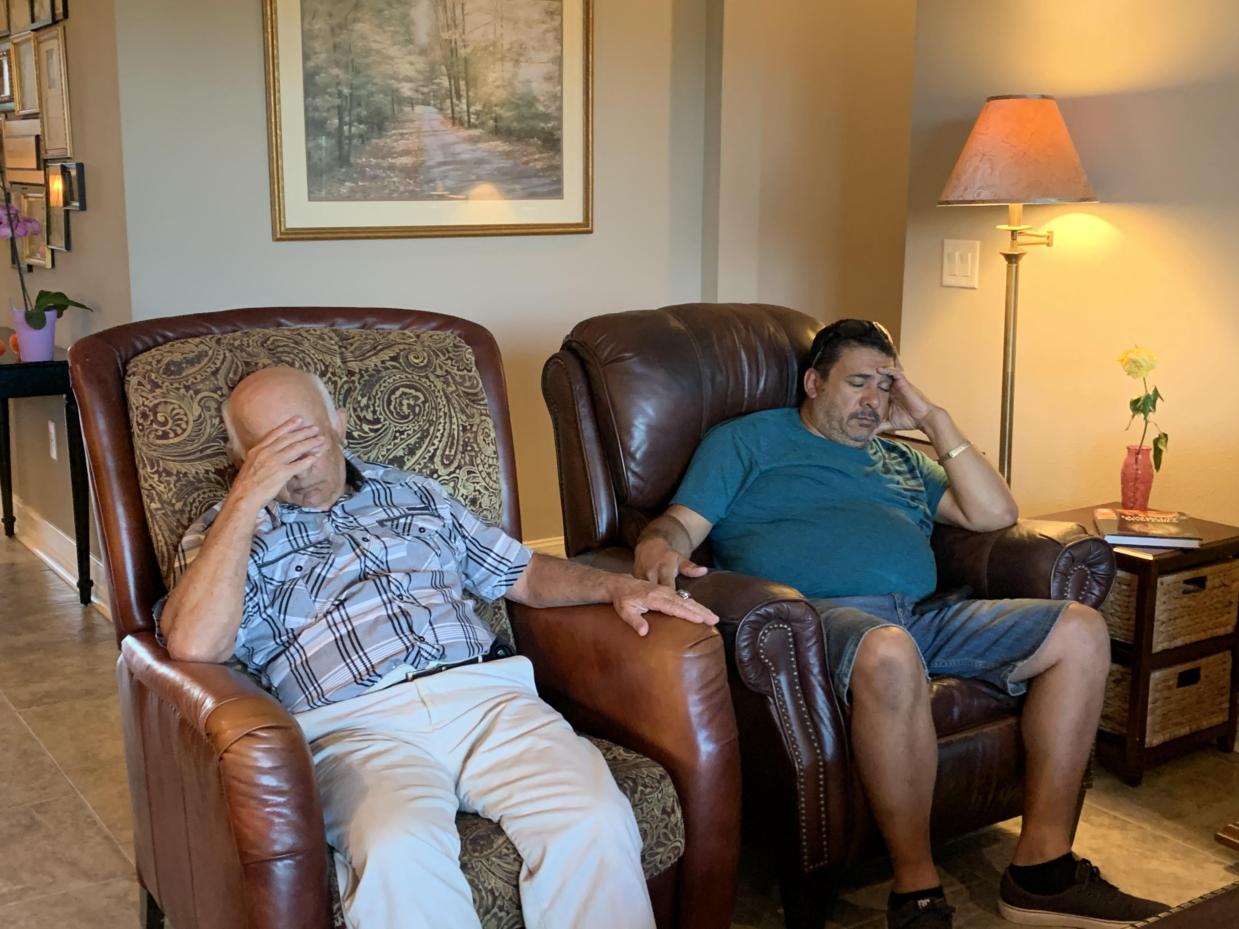 Two men relax in comfortable armchairs, enjoying a peaceful moment together in a living room.