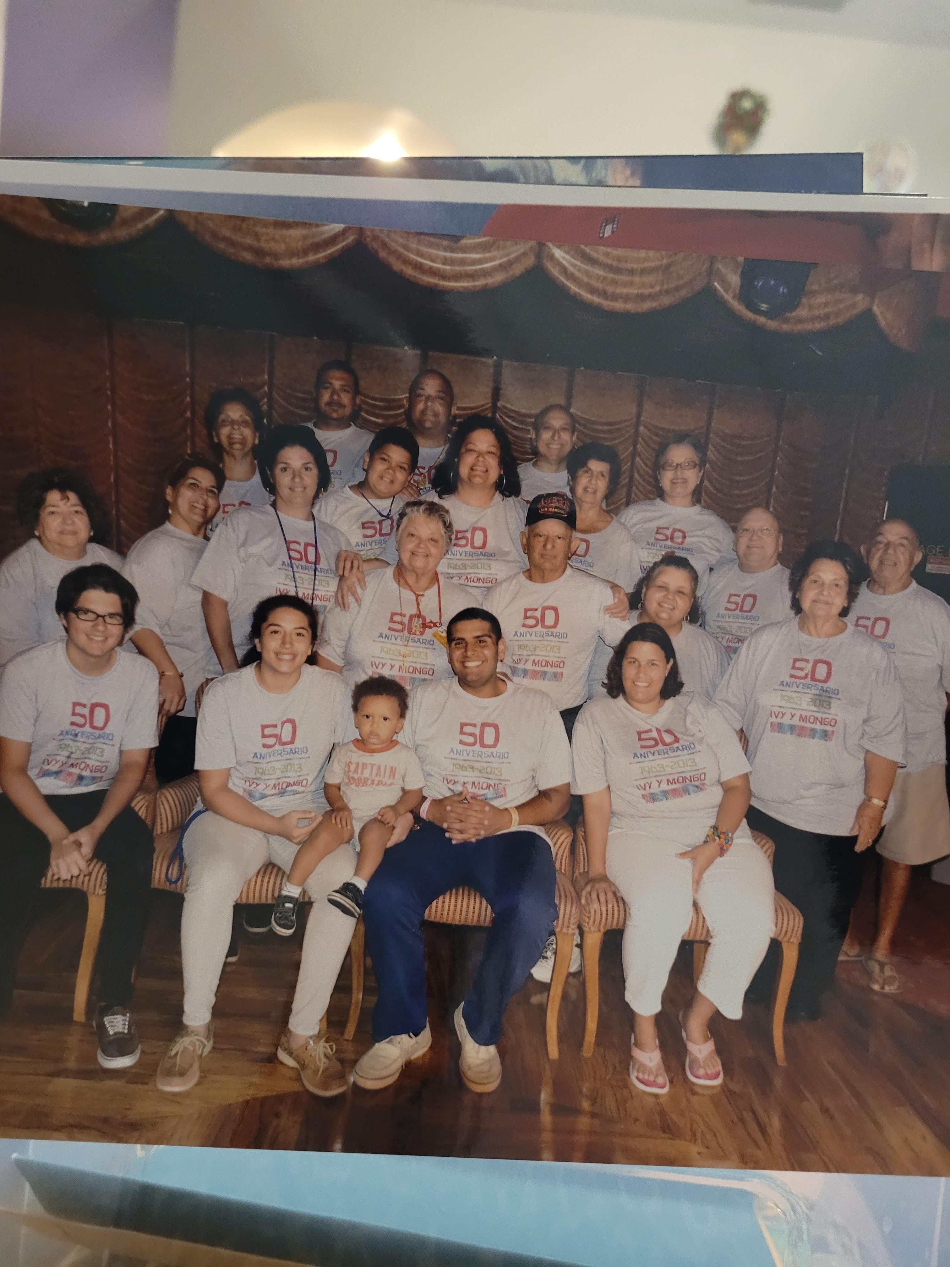 Large gathering of individuals wearing matching shirts, posing happily indoors for a reunion.