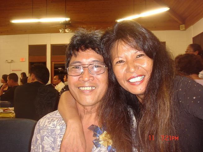 Two friends share a warm moment in a lively community celebration surrounded by smiling faces.