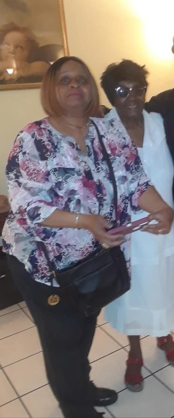 A woman wearing a colorful floral blouse is engaging with another person at a social event.