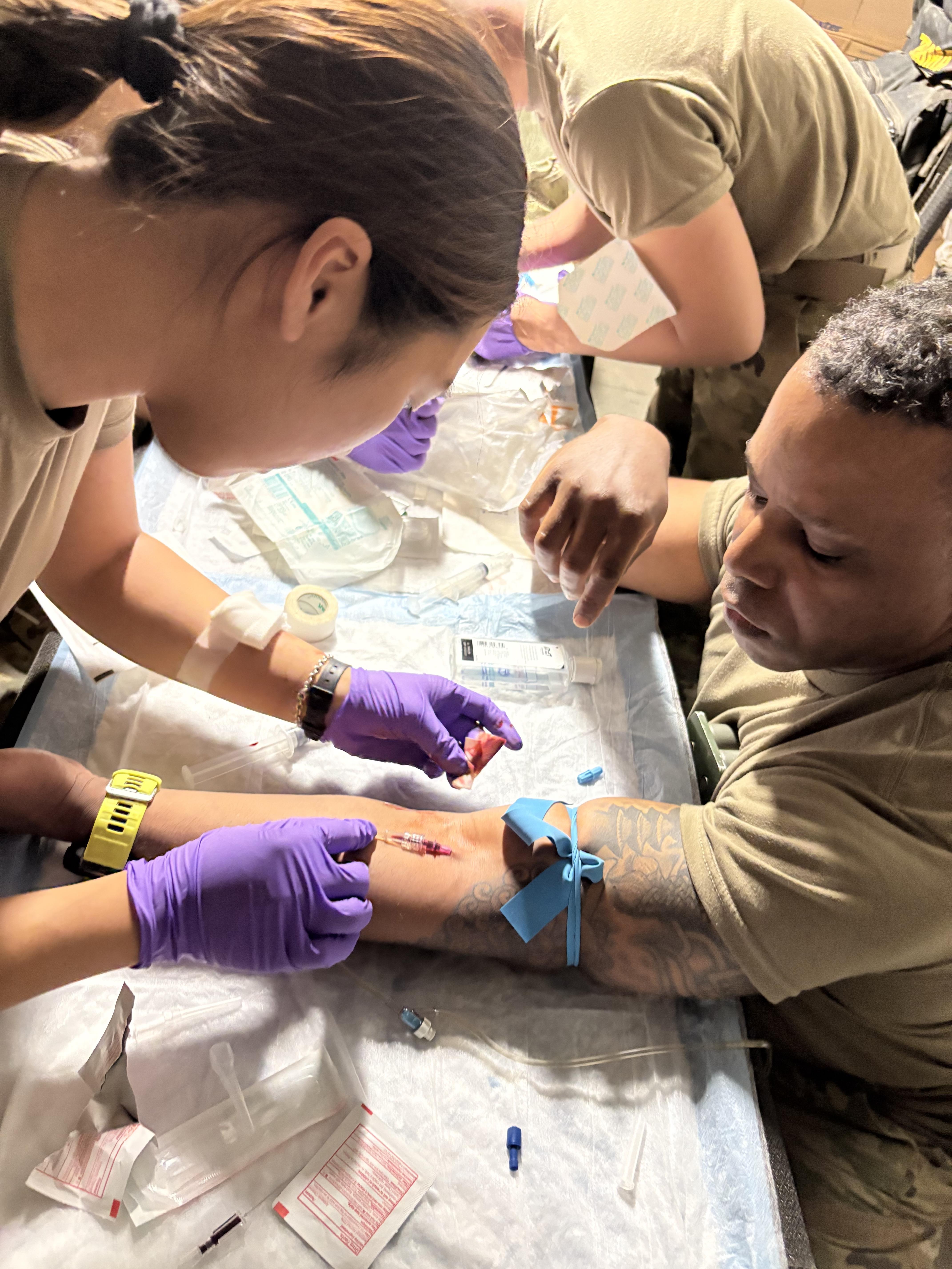 Healthcare workers perform a medical procedure on a service member in a controlled environment.